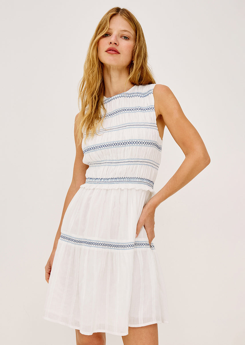 Woman wearing a white dress with blue stripes on a plain background