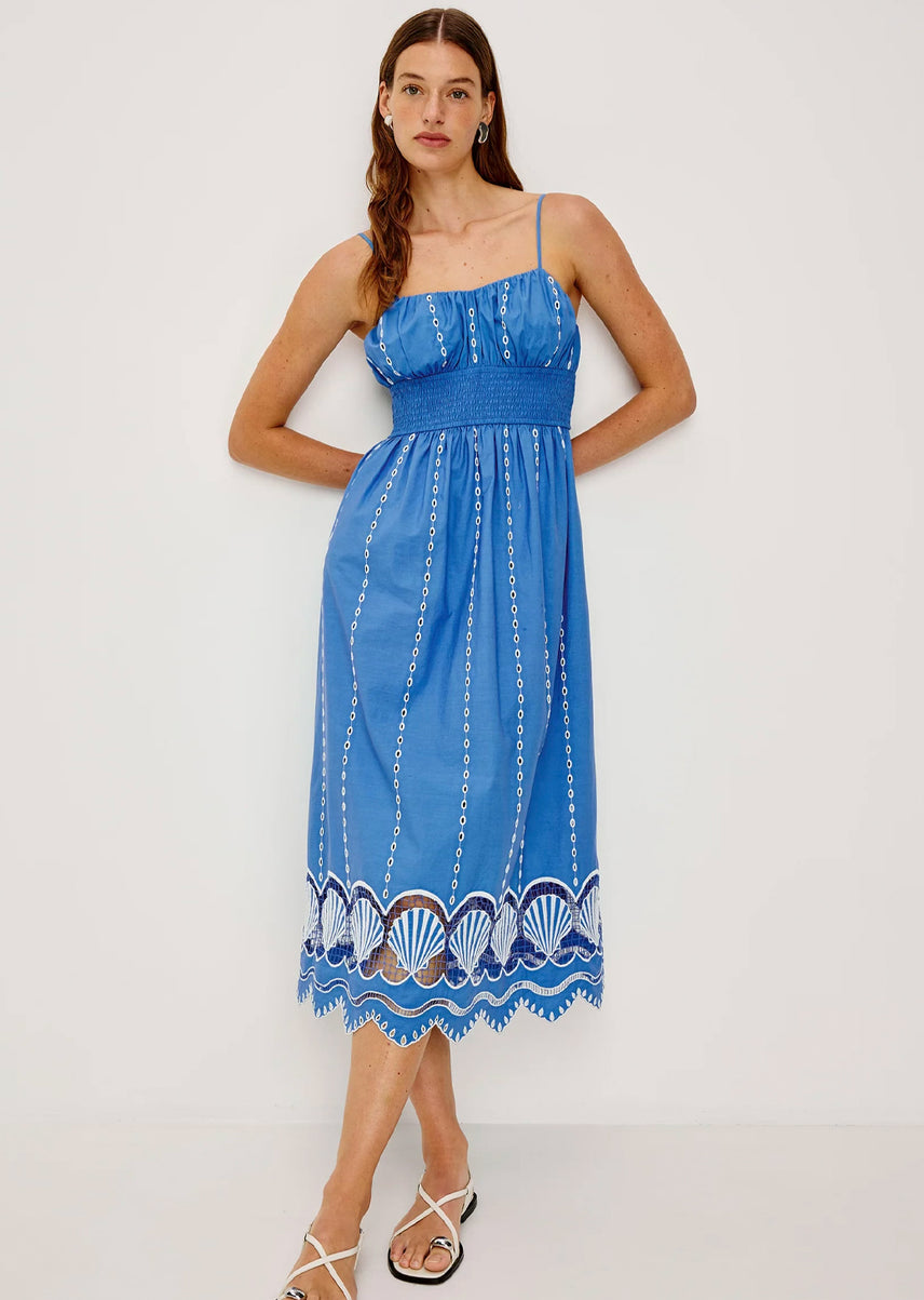 Woman wearing a blue dress with shell patterns on a white background