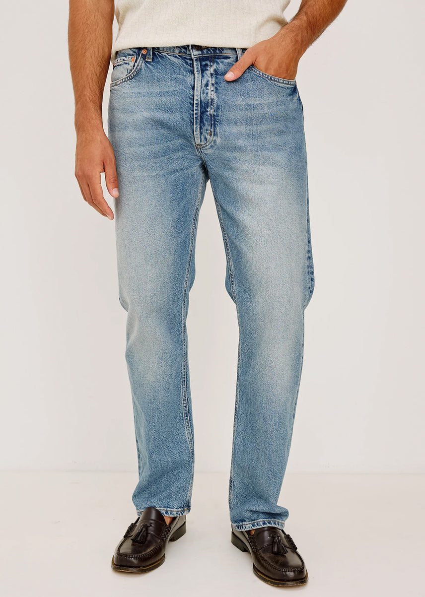 Person wearing light blue jeans on a plain background