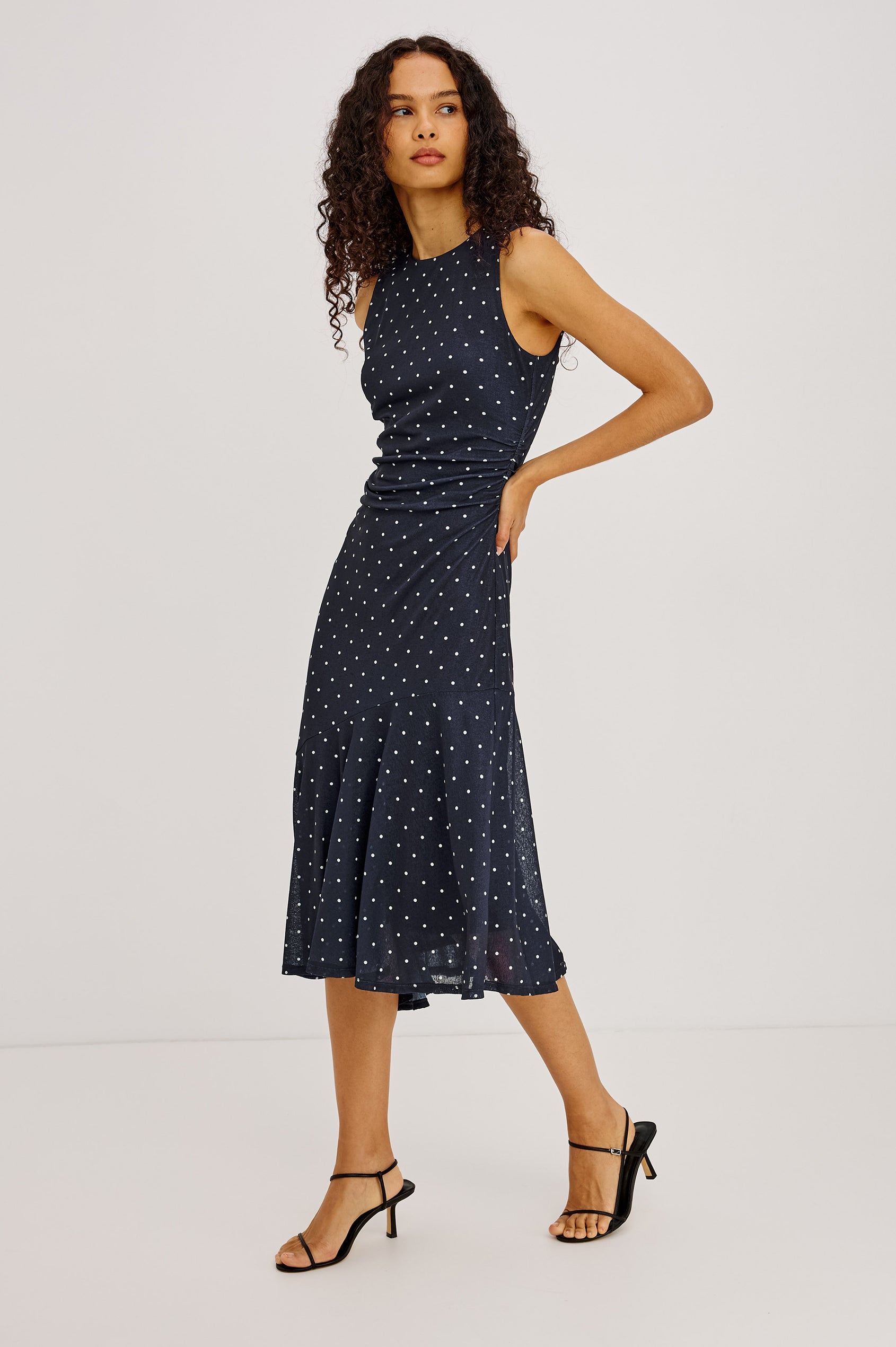 Daija Midi Dress in Self-Lined Mesh With High Neckline, Fitted Bodice, Side Waist Ruching, Bias Cut Skirt, and Asymmetric Hem in Chocolate Polka Dot Colorway - Full Body Side View Featured on Model
