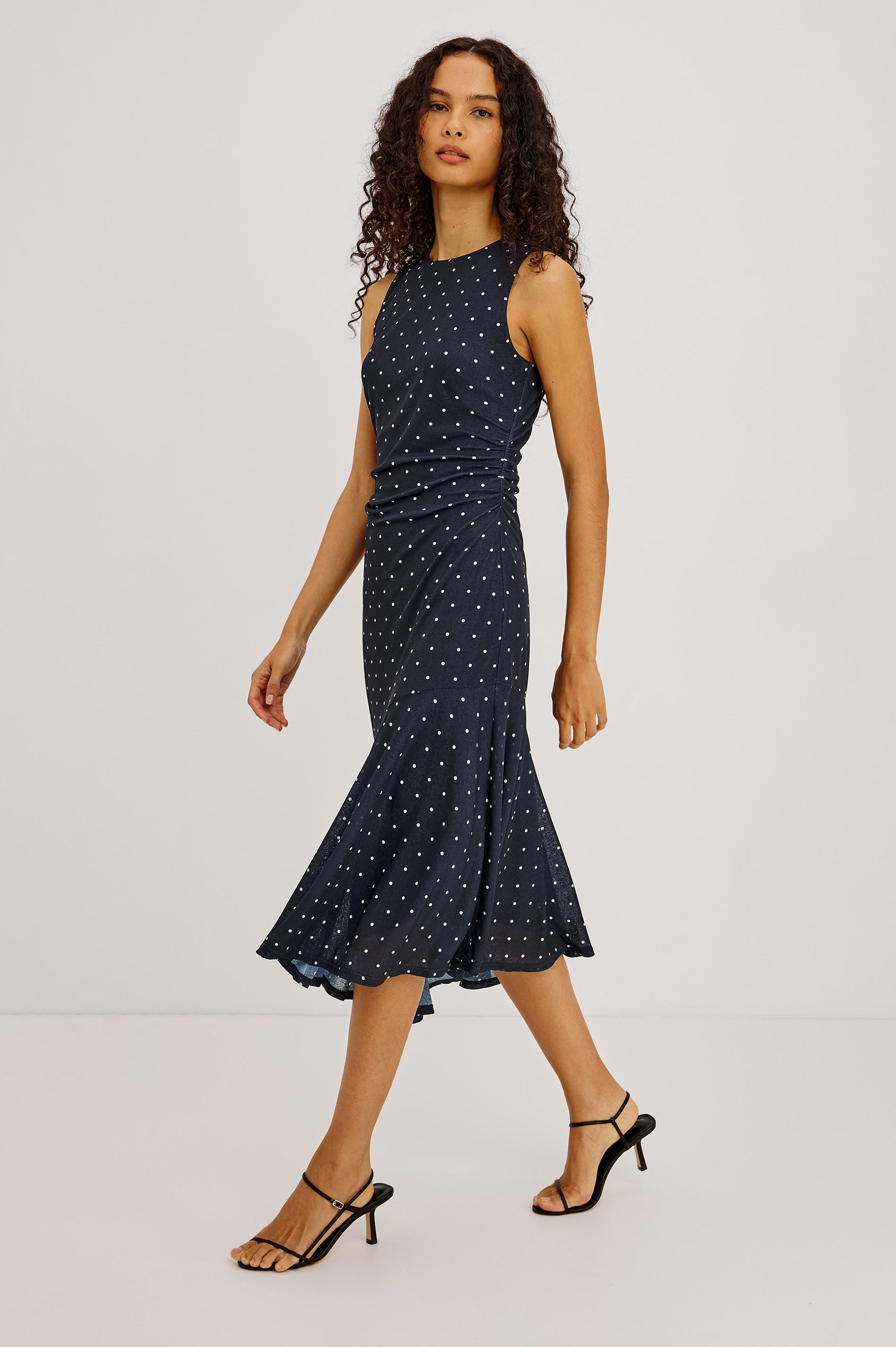 Daija Midi Dress in Self-Lined Mesh With High Neckline, Fitted Bodice, Side Waist Ruching, Bias Cut Skirt, and Asymmetric Hem in Chocolate Polka Dot Colorway - Full Body Side View Featured on Model
