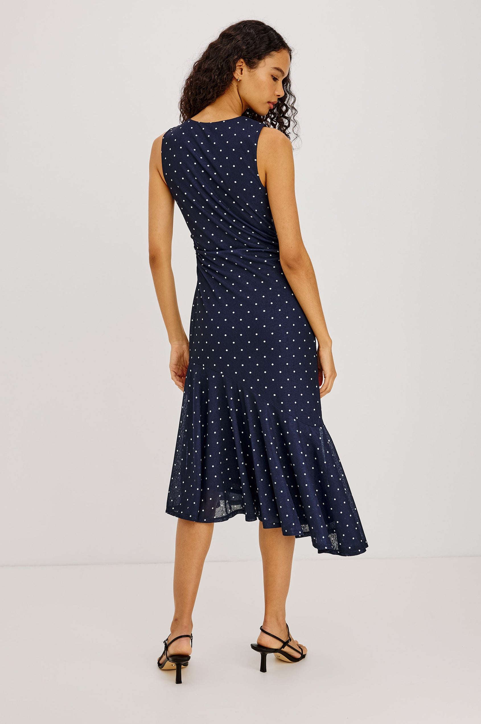 Daija Midi Dress in Self-Lined Mesh With High Neckline, Fitted Bodice, Side Waist Ruching, Bias Cut Skirt, and Asymmetric Hem in Chocolate Polka Dot Colorway - Full Body Back View Featured on Model