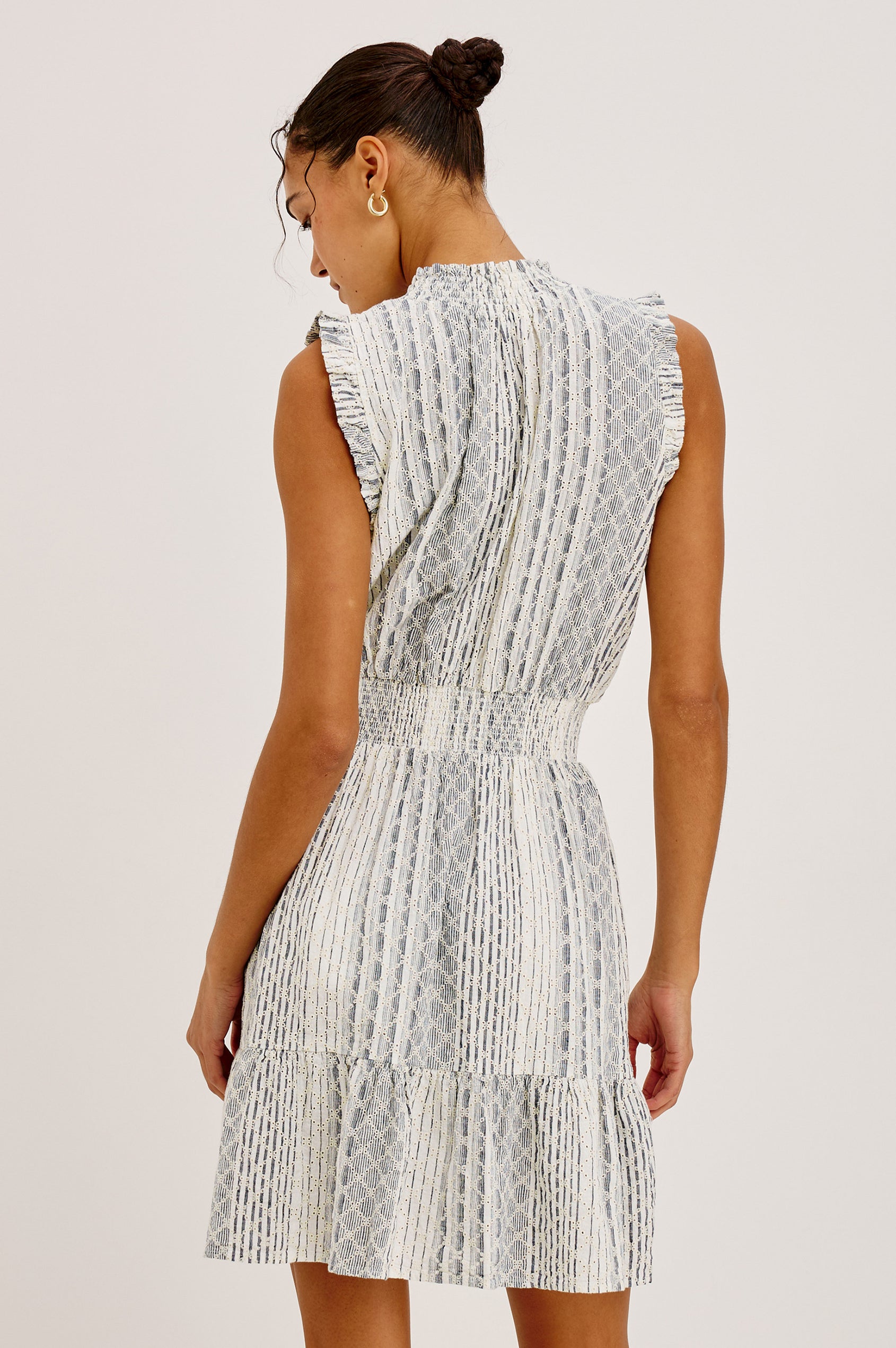 Didi Peasant Style Mini Dress in Luxe Linen With Front Button Placket, Smocked Waist, and Tiered Hem in Striped Eyelet Colorway - Full Body Back View Featured on Model