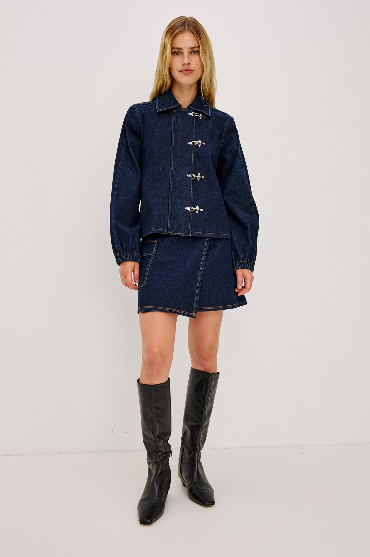 Dillon Mini Skirt in Midweight Denim With Mid-Rise, Asymmetric Wrap Design, Toggle Closure at Side Waist, Contrast Topstitching, and Utility Patch Pocket in Rinse Indigo Colorway - Full Body Front View Featured on Model