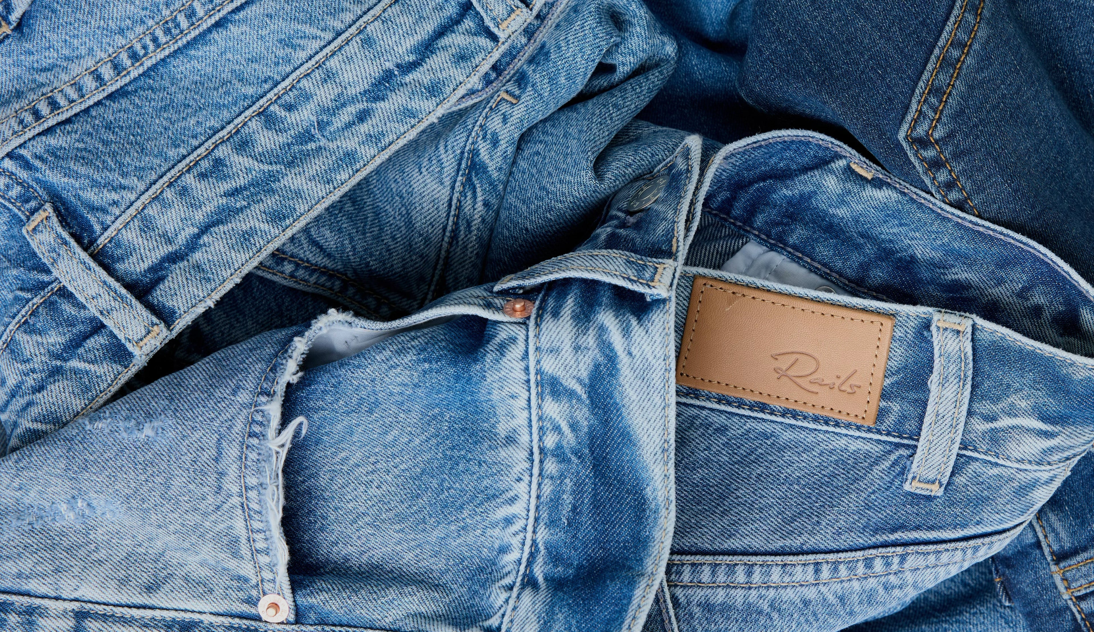 Stack of blue jeans with a brand label on a blue background