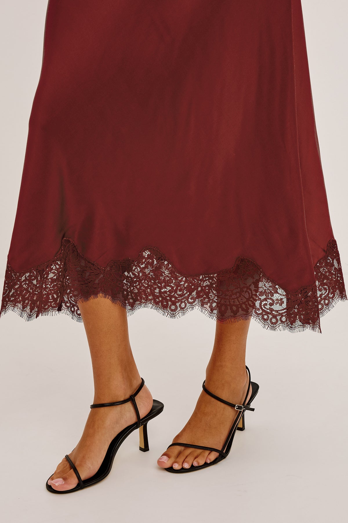 Ebony Midi Skirt Bias Cut in Satin With Clean Elastic Waistband, Pull-On Fit, and Tonal Lace Trim at Hem in Crimson Colorway - Lower Body Front View Featured on Model