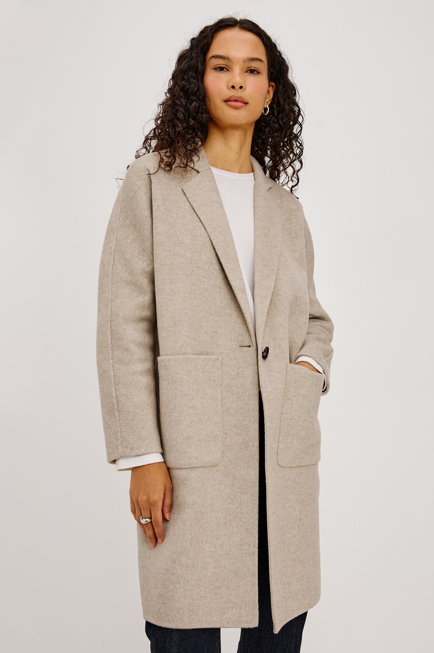 Everest Coat in Heavy Wool Blend With Longline Cut, Slightly Oversized Relaxed Fit, Lapel Collar, Single-Button Front, and Front Patch Pockets in Oat Herringbone Colorway - Upper Body Front View Featured on Model