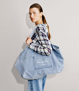 Woman wearing a plaid top with denim bottoms and a Rails denim tote bag