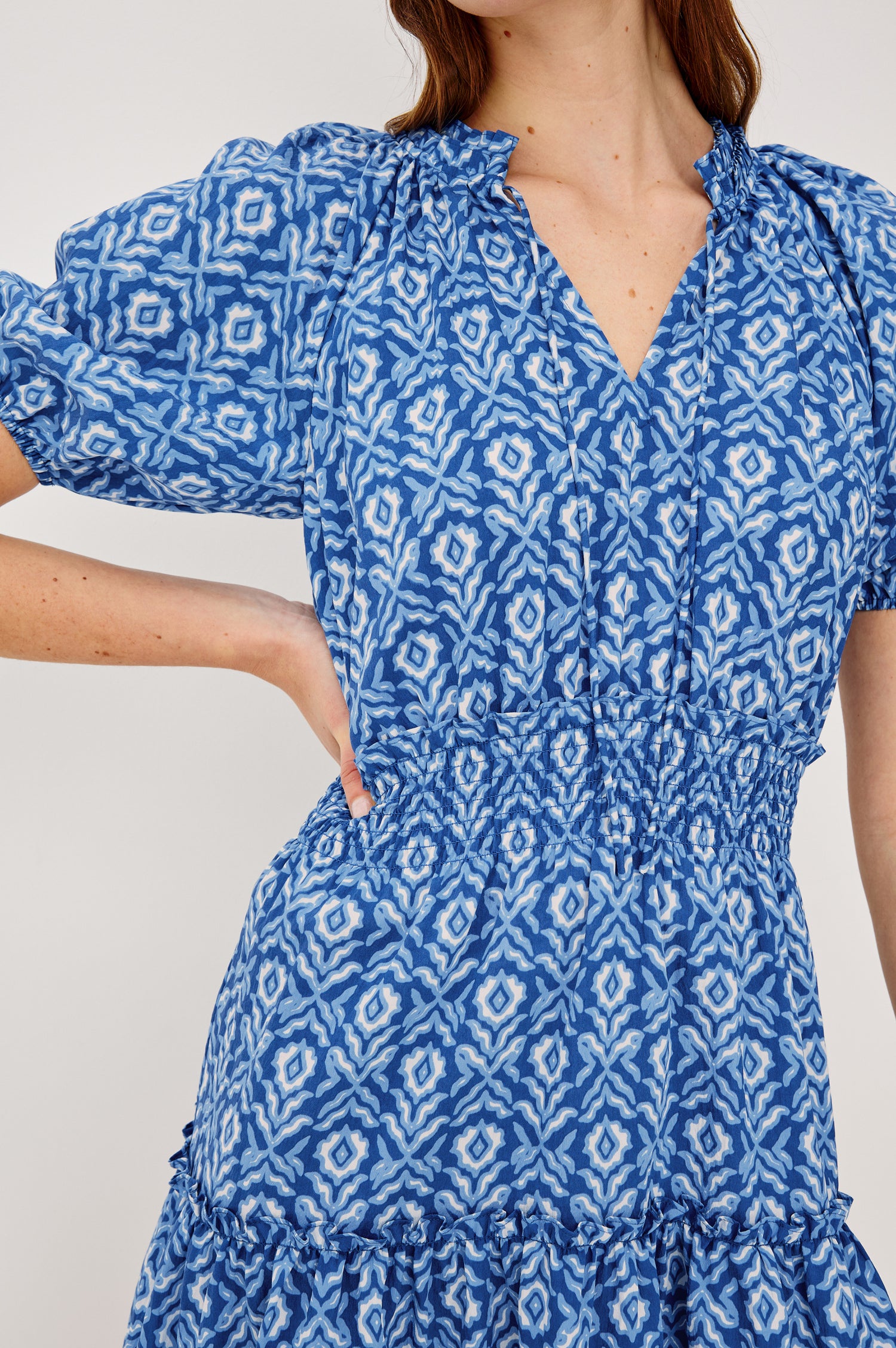 Fiorella Mini Dress in Crinkle Chiffon With Split V-Neck and Adjustable Ties Short Puff Sleeves Shirred Waist and Lined Tiered Skirt in Blue Ikat Colorway - Upper Body Close Up View Featured on Model