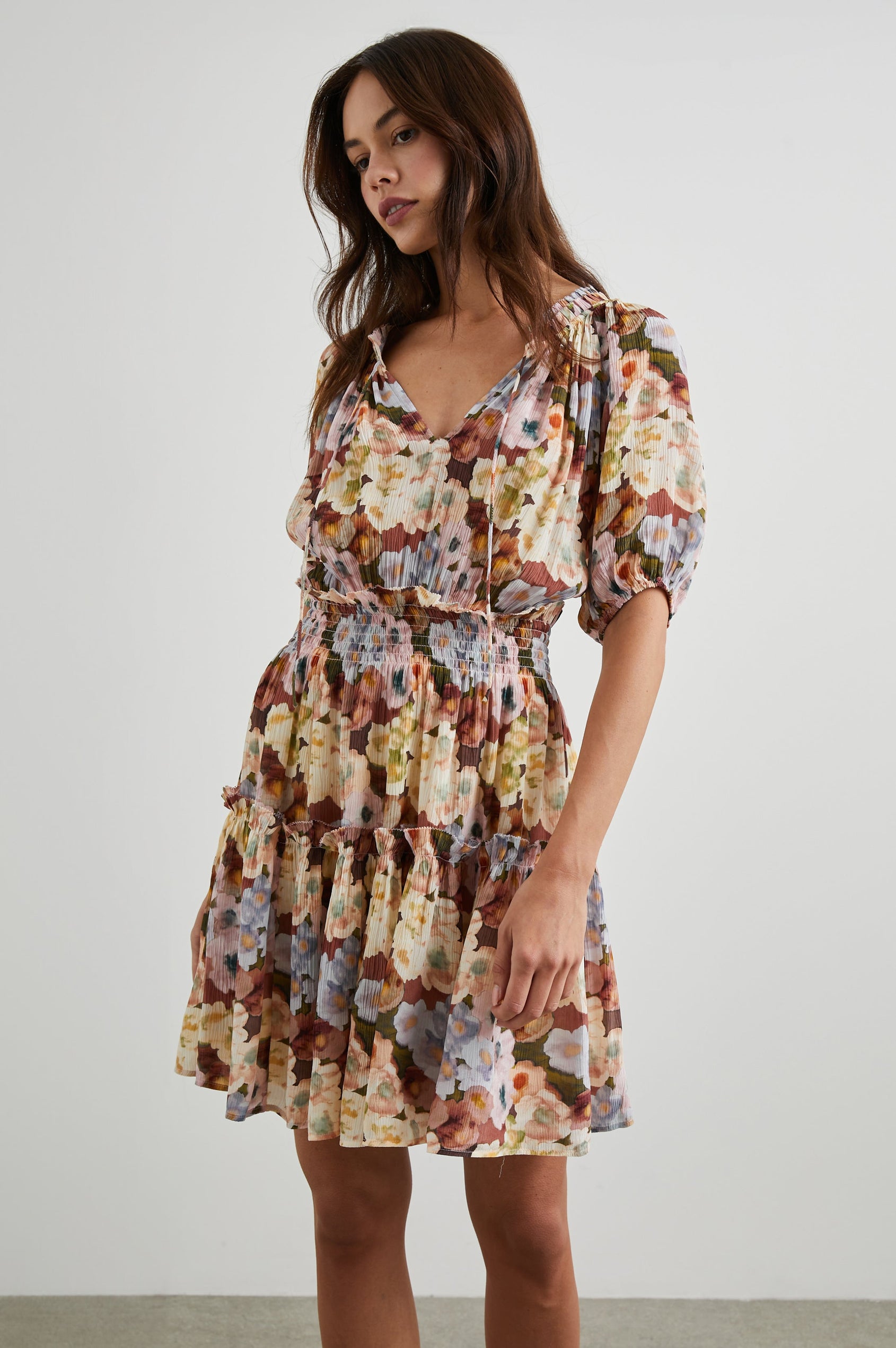 Fiorella Short-Sleeve, Above-Knee Dress with a Shirred Collar and Waist, V-neckline with Ties, Puff Sleeves and a Tiered Skirt in Painted Floral Colorway, with browns, yellows and blues - Front View Featured on Model