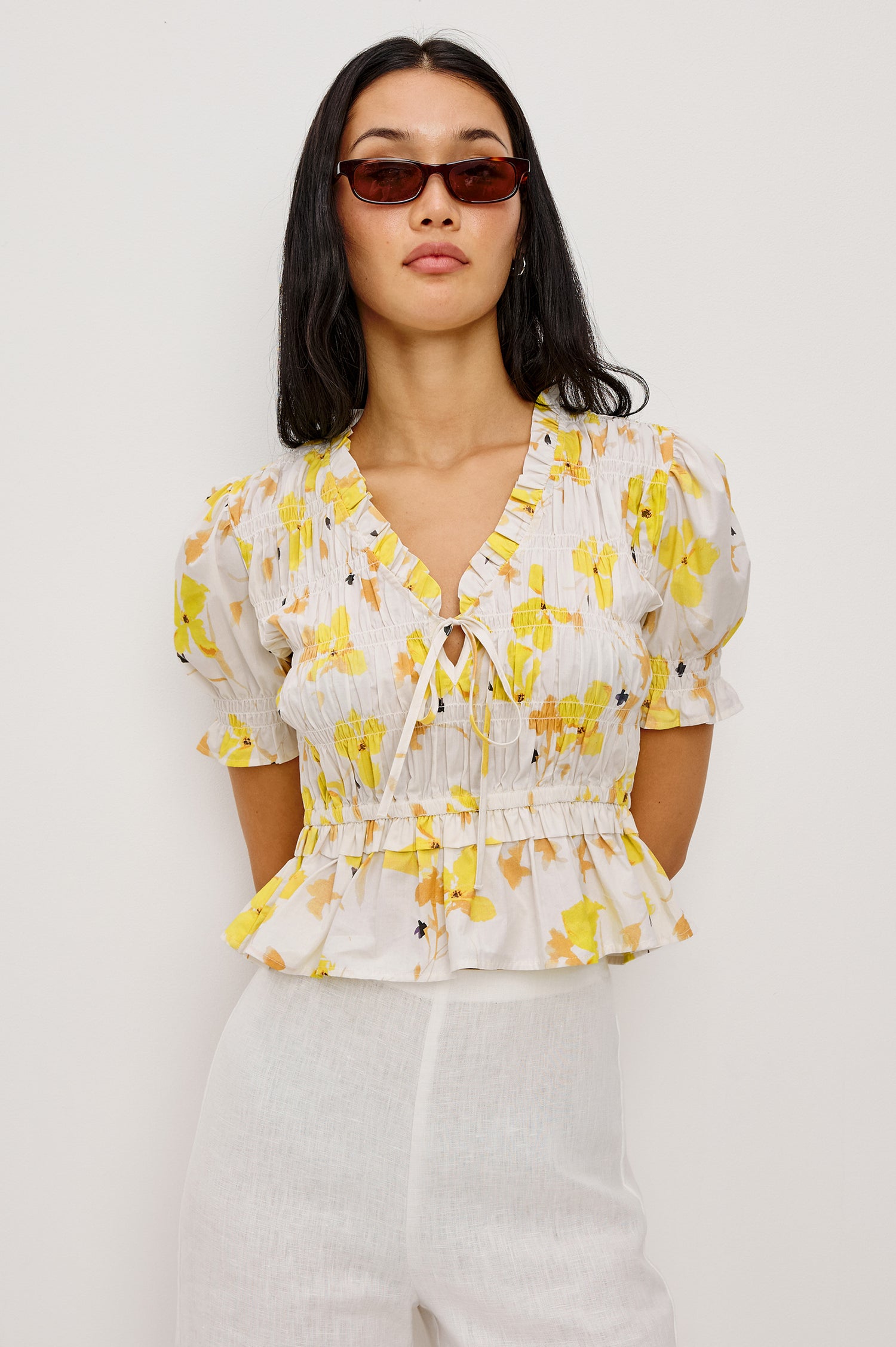 Fontaine Cropped Top in Cotton Poplin With Fitted Smocked Body V-Neckline With Center-Front Ties Short Puff Sleeves Rufle Trim and Peplum Hem in Tossed Daffodils Colorway - Upper Body Front View Featured on Model