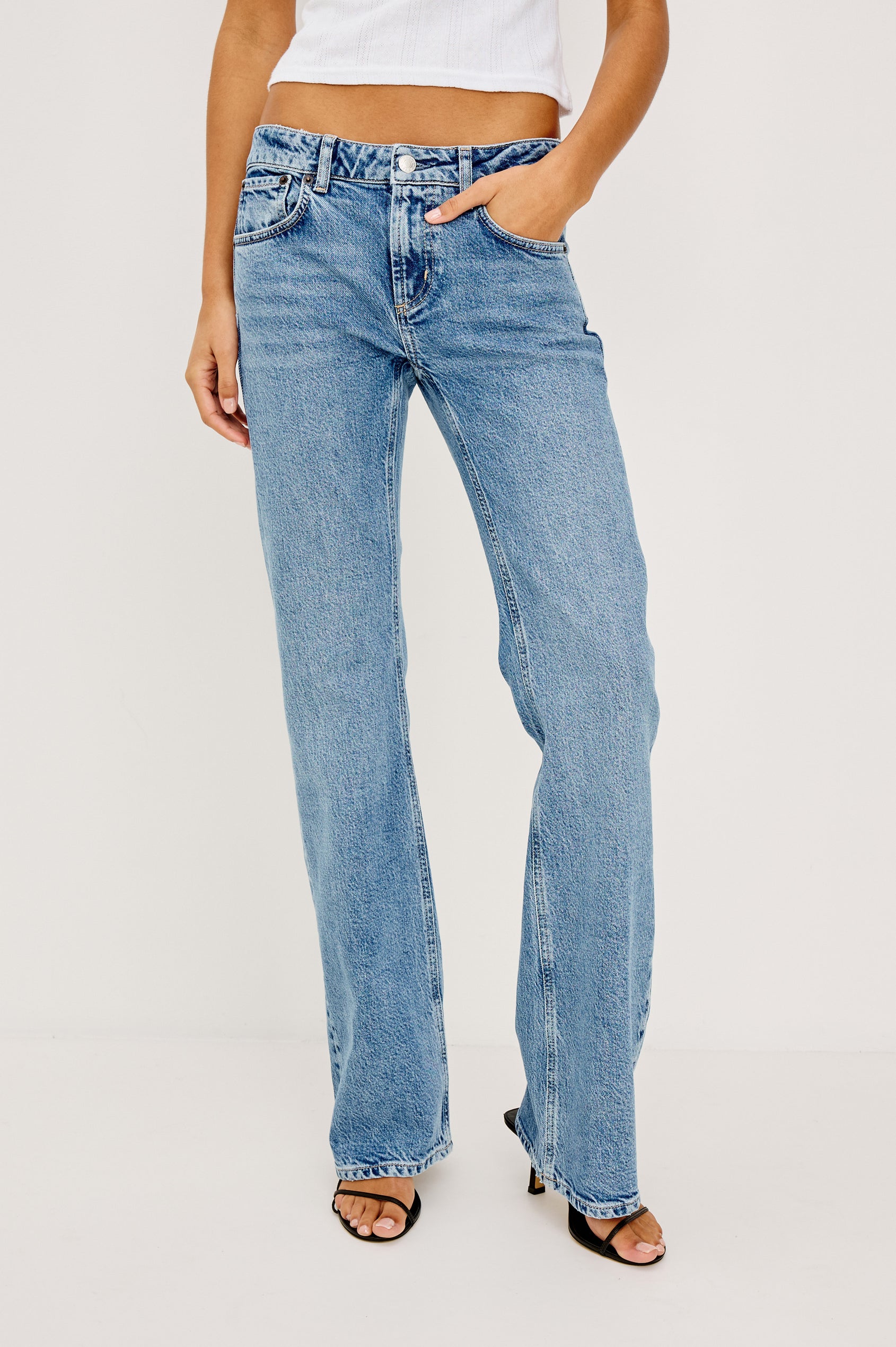 Fremont Petite Low Rise Bootcut Jean in Light Stretch Denim With Extended Inseam, 5-Pockets, Distressed Details, Belt Loops, and Zip-Fly Closure in Old Indigo Colorway - Lower Body Front View Featured on Model