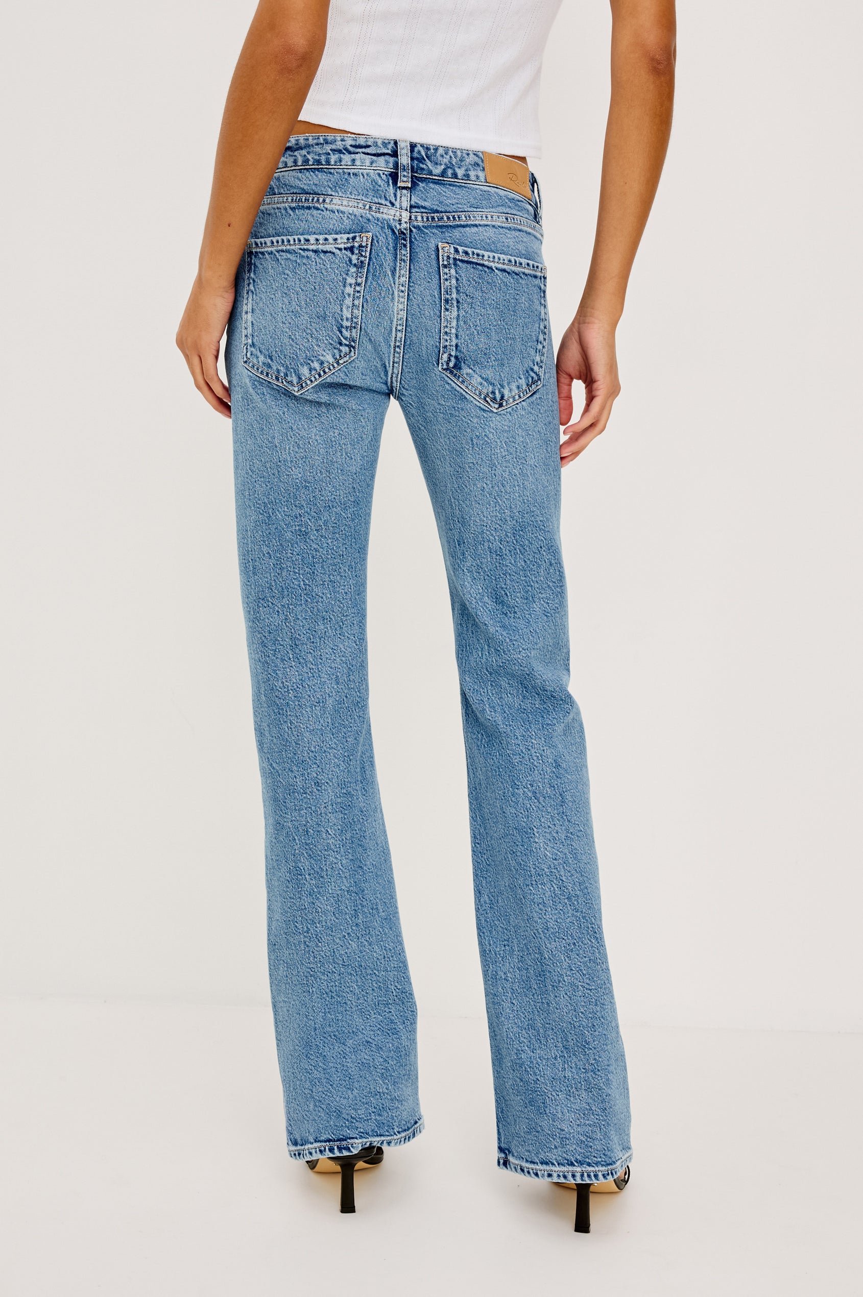 Fremont Petite Low Rise Bootcut Jean in Light Stretch Denim With Extended Inseam, 5-Pockets, Distressed Details, Belt Loops, and Zip-Fly Closure in Old Indigo Colorway - Lower Body Back View Featured on Model