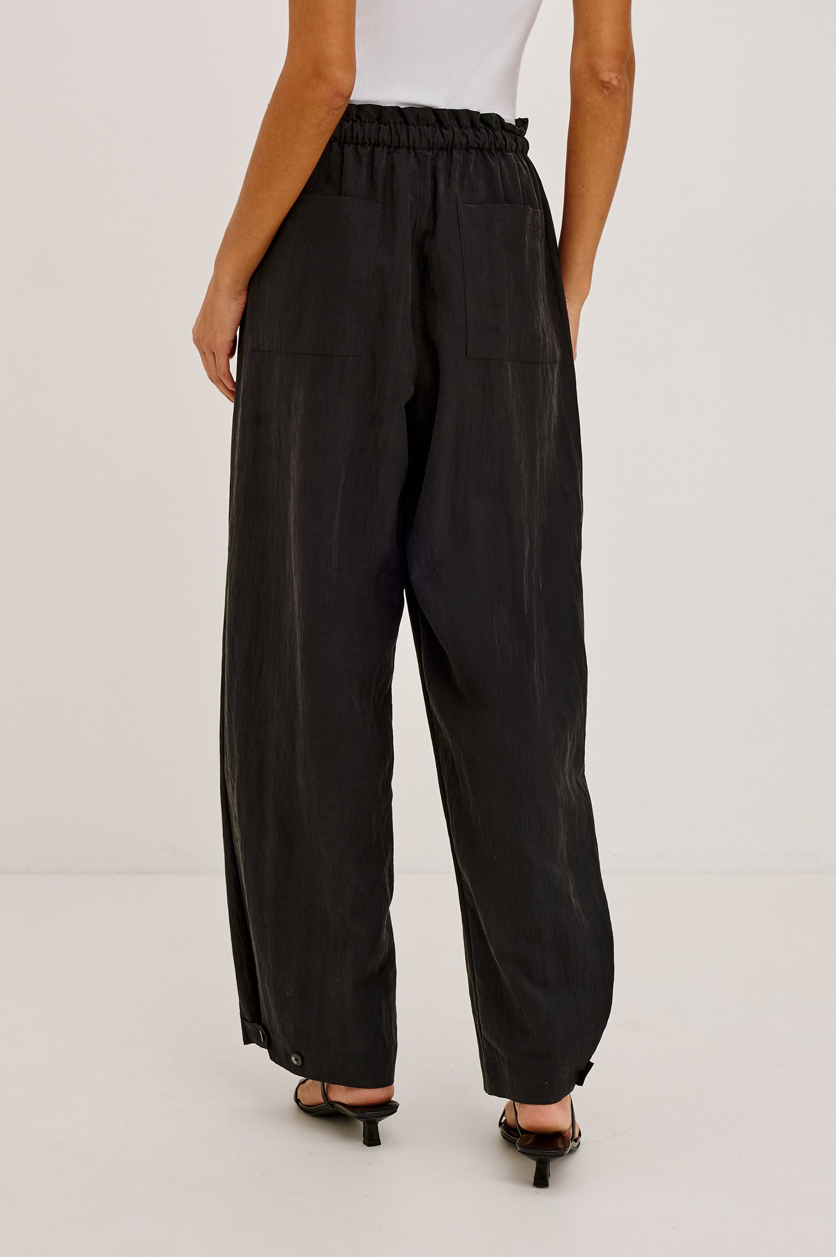 Fulham Pant in Nylon With Mid-Rise Wide Leg Fit, Front Pleats, Back Patch Pockets, Back Hem Buttons to Adjust Leg Wide to Slim in Black Colorway - Lower Body Back View Featured on Model