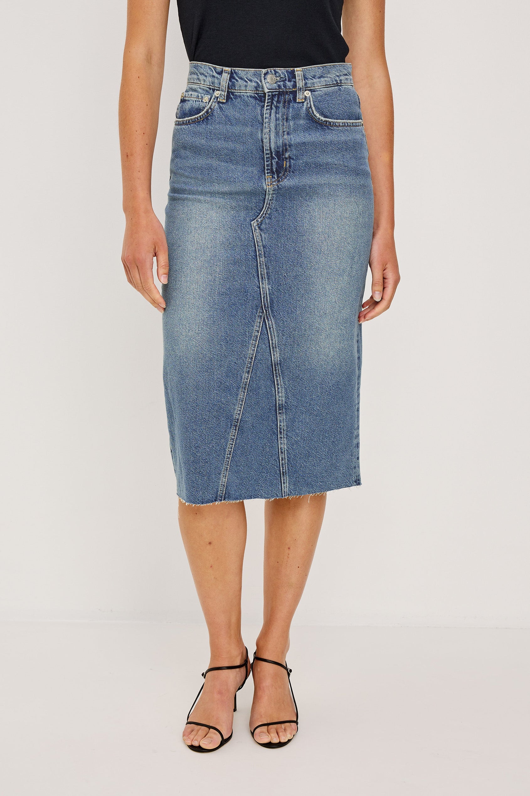 Highland Denim Midi Skirt with a Raw Hem, a Back Vent, Additional Front Seams, Belt Loops, Two Front Pockets plus a Coin Pocket and Two Back Patch Pockets in Vintage Sapphire Colorway - Front View Featured on Model 