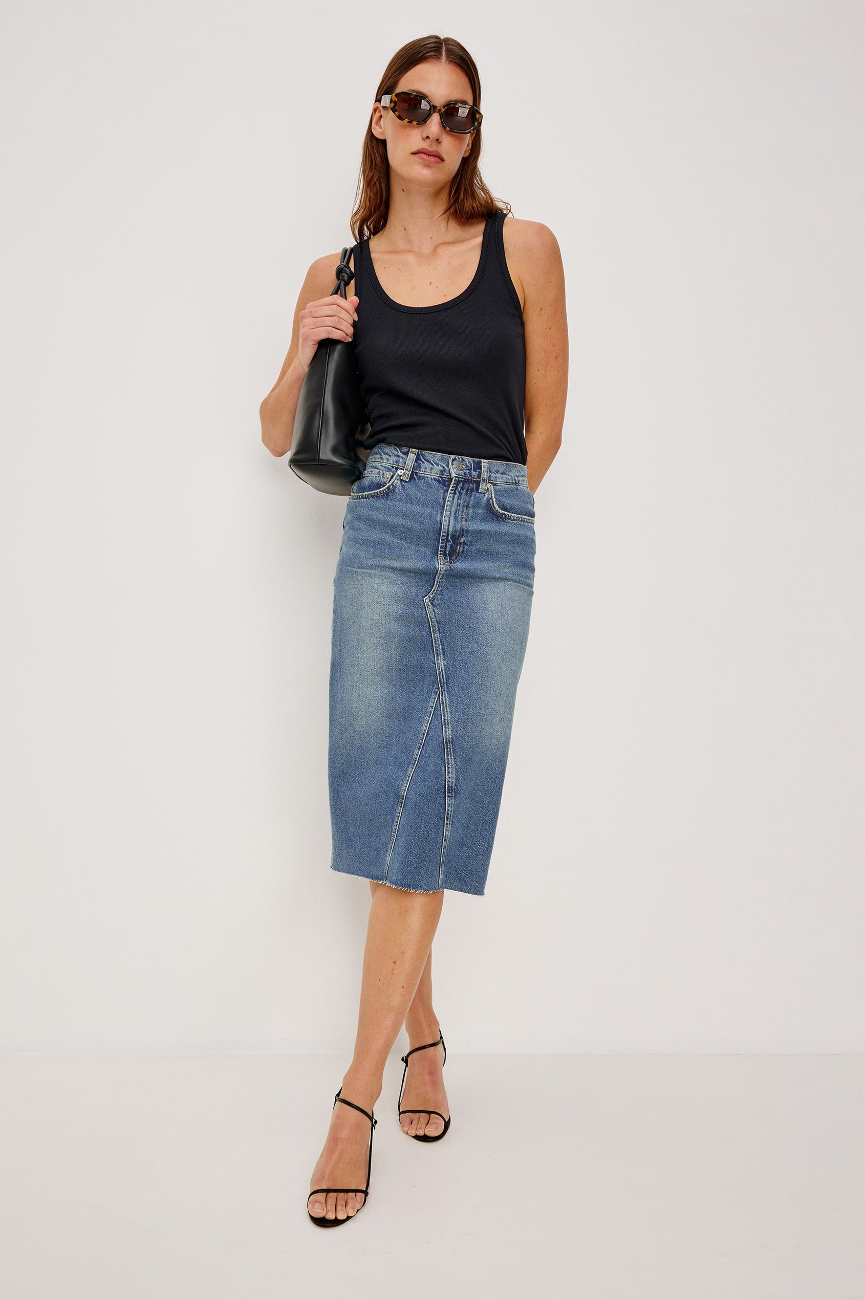 Highland Denim Midi Skirt with a Raw Hem, a Back Vent, Additional Front Seams, Belt Loops, Two Front Pockets plus a Coin Pocket and Two Back Patch Pockets in Vintage Sapphire Colorway - Front Full Body View Featured on Model 