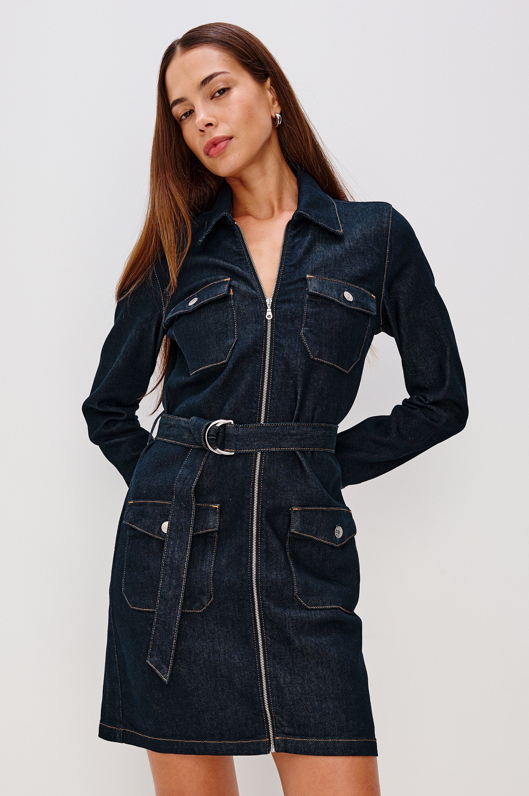 Jefferson is a long sleeve mini denim dress, featuring utility-inspired details and an o-ring adjustable waist belt in Midnight Blue colorway, a rinse wash. Front view featured on model.