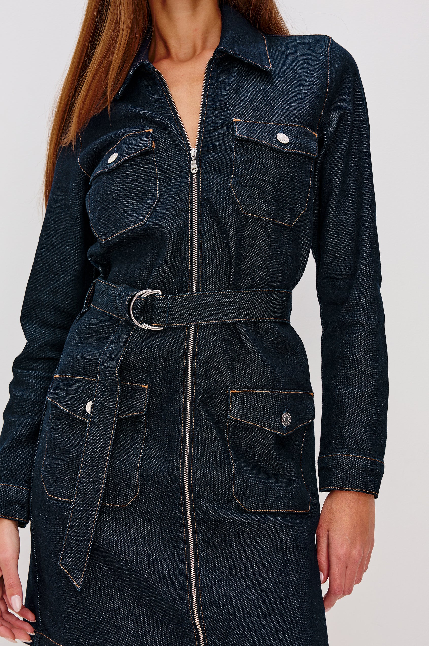 Jefferson is a long sleeve mini denim dress, featuring utility-inspired details and an o-ring adjustable waist belt in Midnight Blue colorway, a rinse wash. Front detail view featured on model.