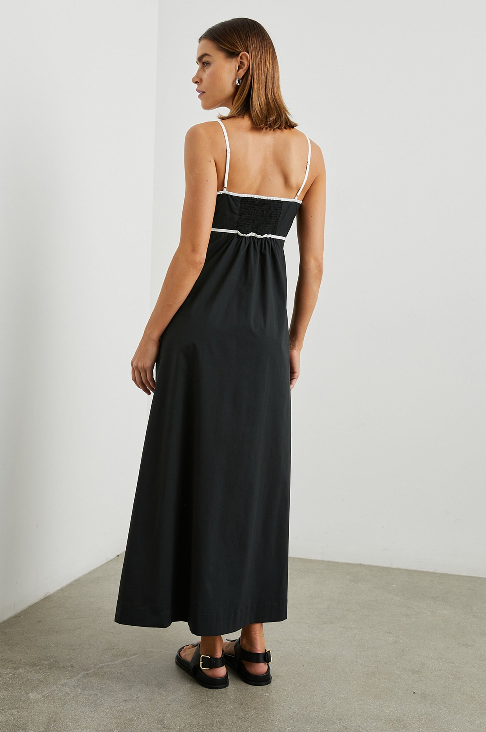 Jessa Sleeveless Maxi Dress with Adjustable Spaghetti Straps, a Deep V Neck with a Cutout, a Shirred Back and White Trim on the Bodice in Black Colorway - Back Full Body View Featured on Model 