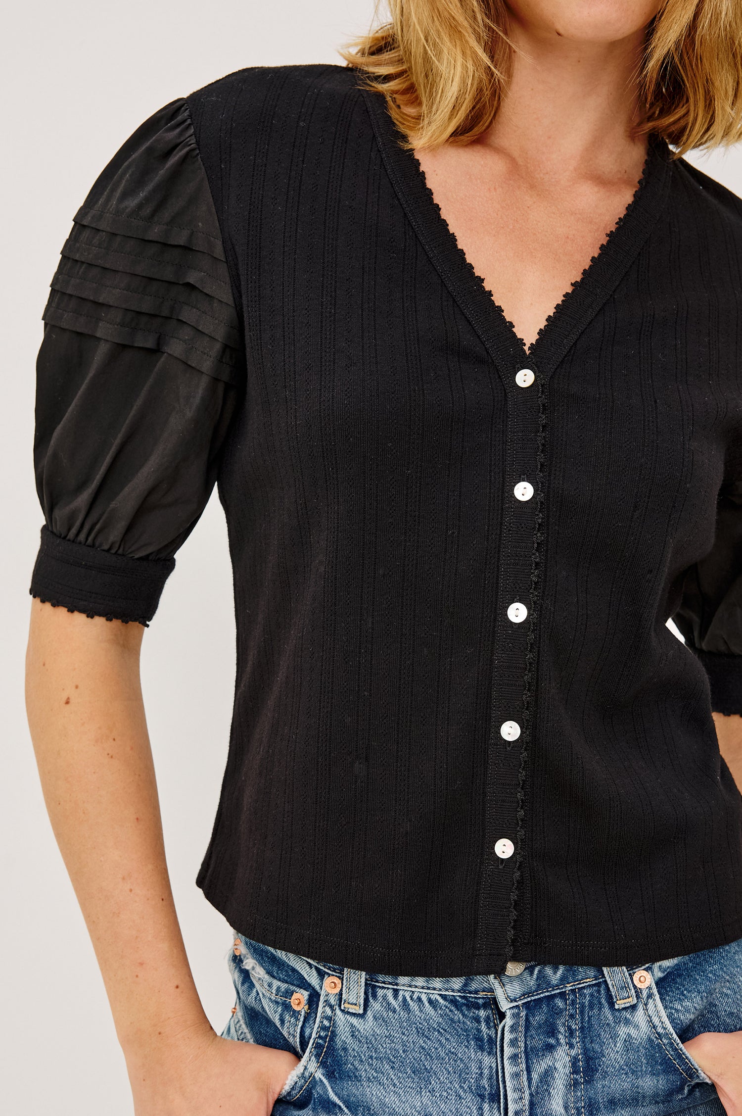 Jessie Top in Pointelle With V-Neckline, Front Buttons, Short Cuffed Puff Sleeves, and Relaxed Fit in Black Colorway - Upper Body Front View Featured on Model