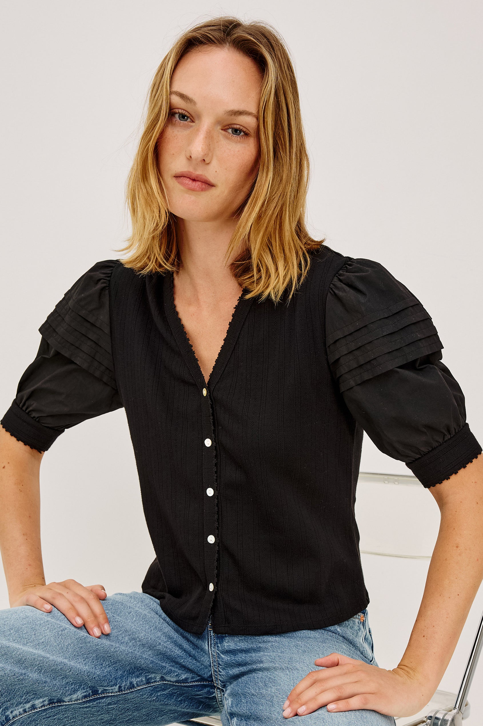 Jessie Top in Pointelle With V-Neckline, Front Buttons, Short Cuffed Puff Sleeves, and Relaxed Fit in Black Colorway - Upper Body Front View Featured on Model
