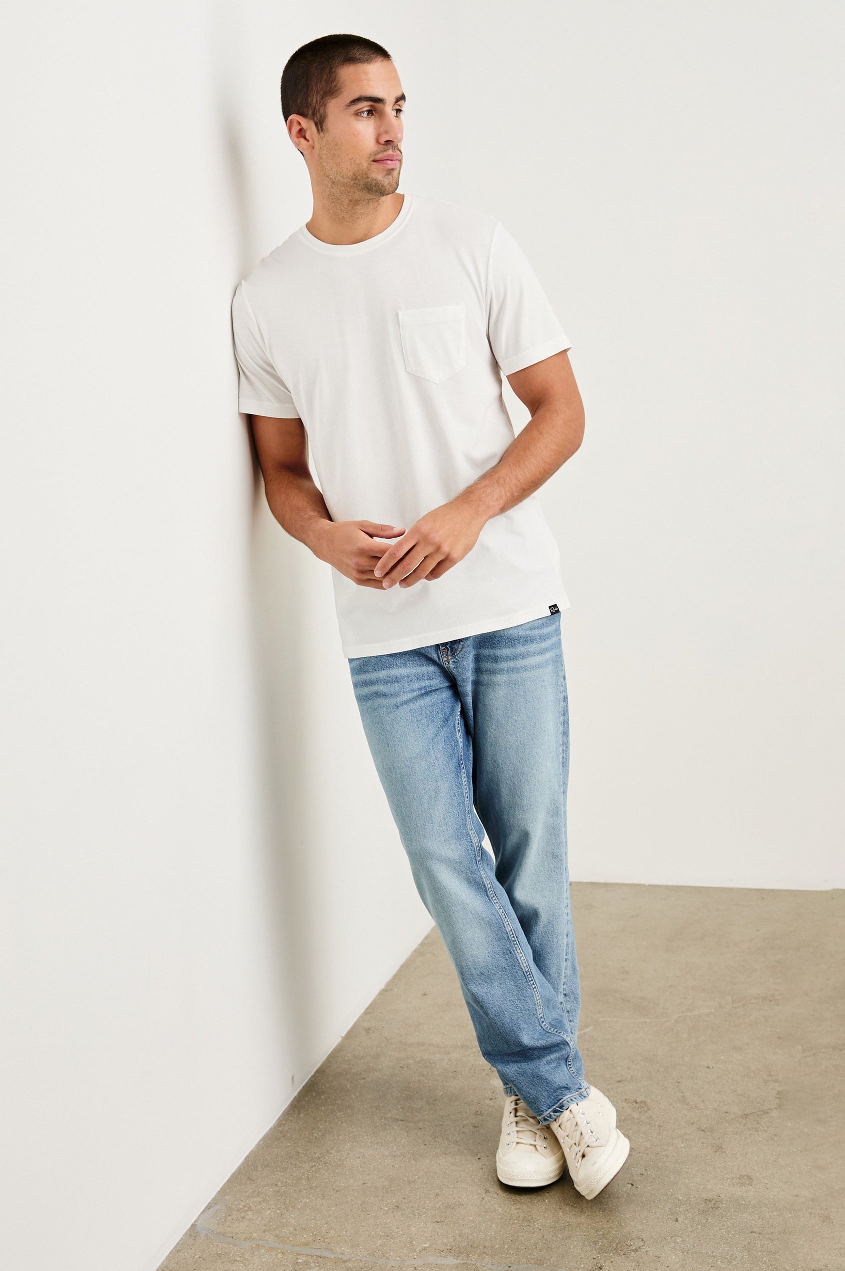 Johnny cotton jersey t-shirt with front chest pocket in White - full body front view on model, leaning against wall