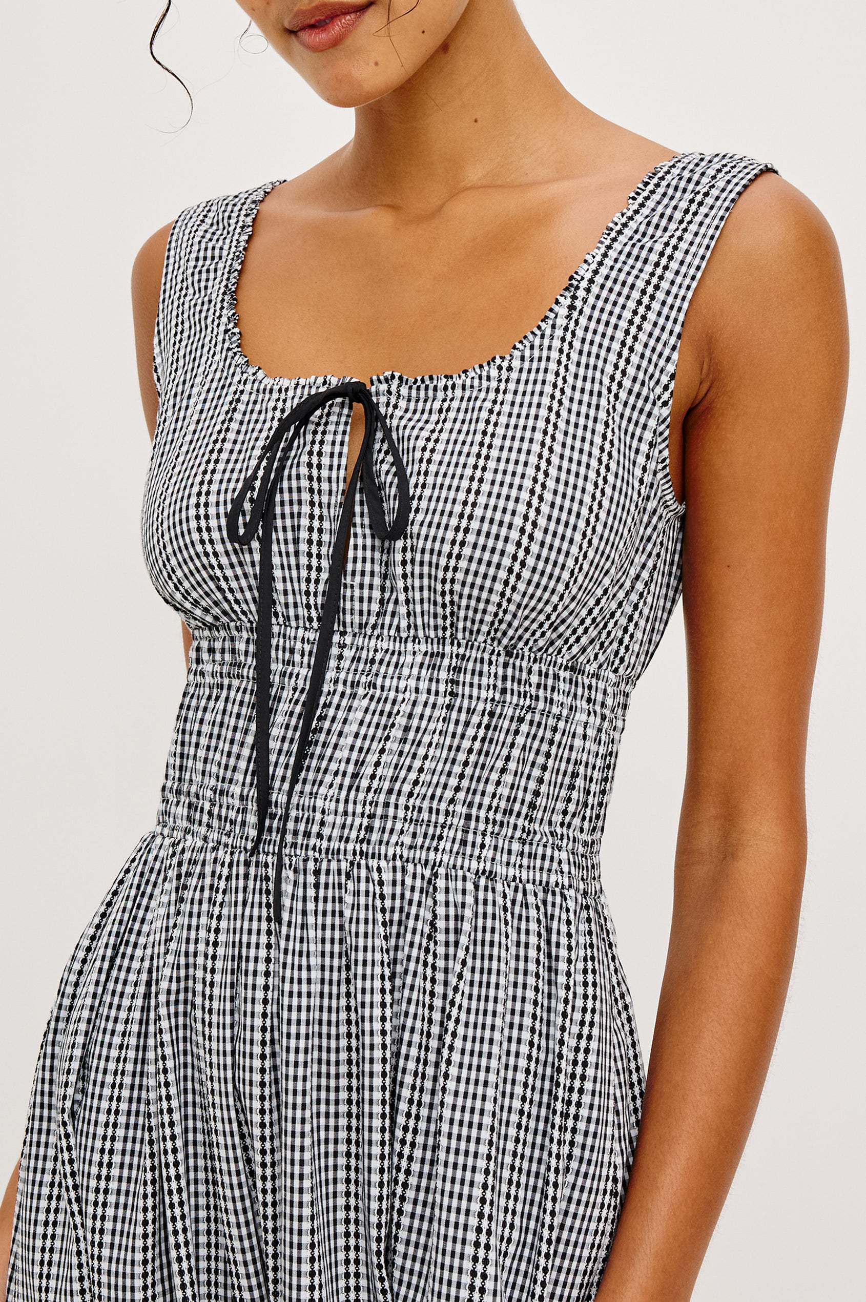 Jordie Maxi Dress in Cotton Poplin With A-Line Silhouette Rounded Square Neckline Rufle Trim Center-Front Bust Cutrout With Self-Ties Smocked Waist Side Pockets and Fully Lined Skirt in Black Gingham Colorway - Upper Body Front Close Up View Featured on Model