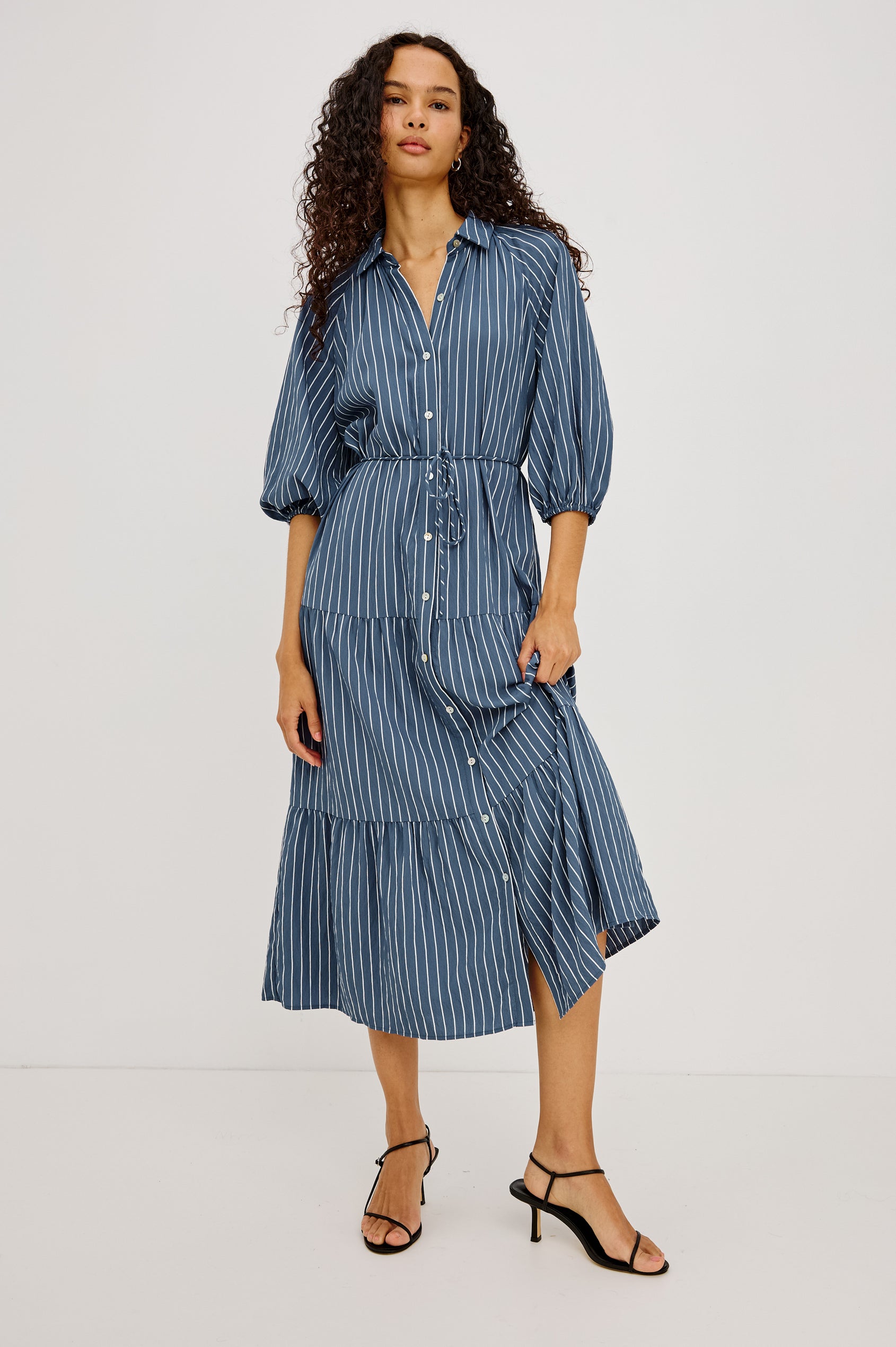 June Maxi Dress in Soft Crinkle Shirting With Three-Quarter Puff Sleeves, Point Collar, Full Front Button Placket, and Self-Tie Waist in Washed Indigo Stripe Colorway - Full Body Front View Featured on Model
