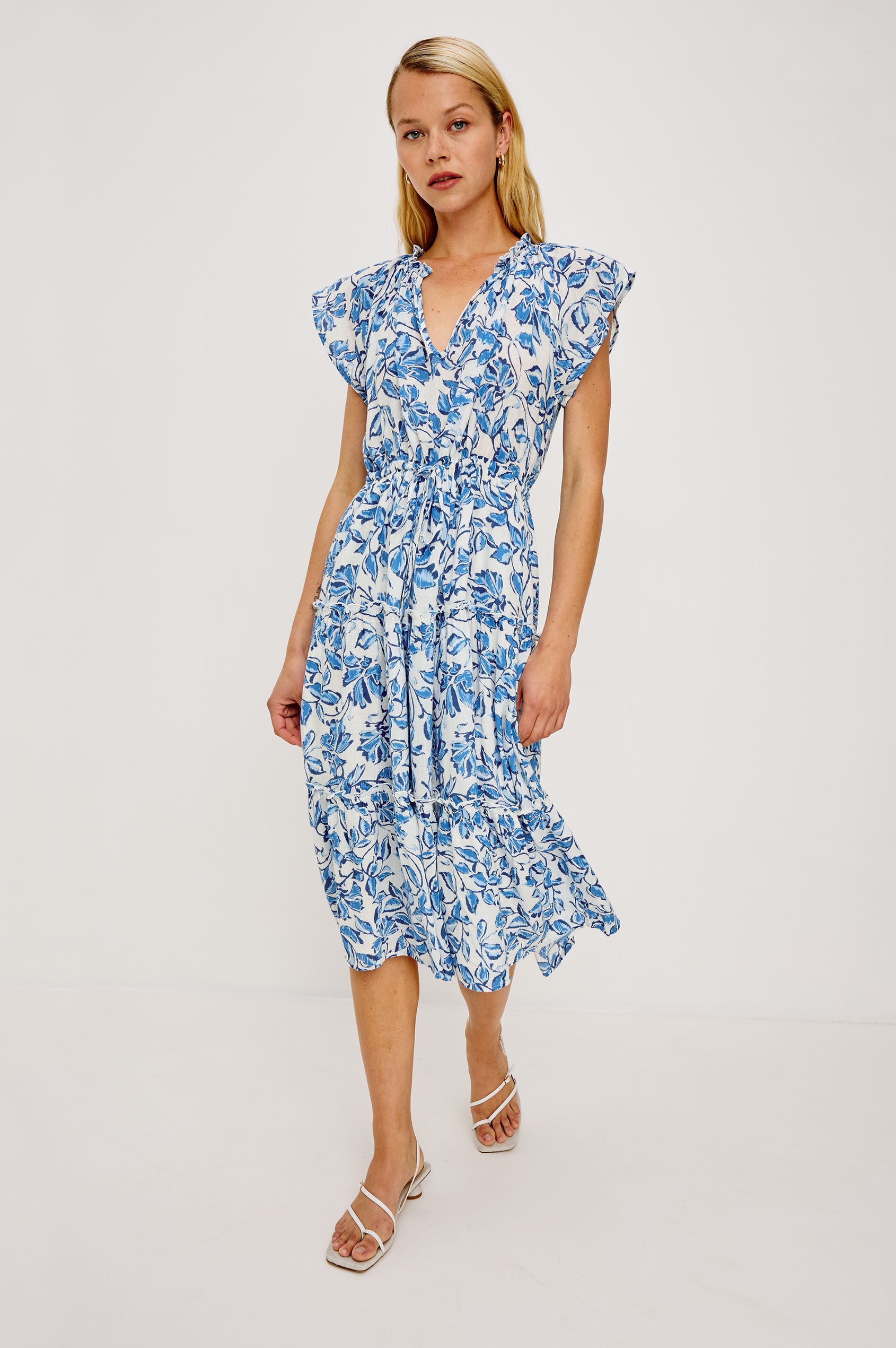 Juni Maxi in Linen With Ruffled Split V-Neckline Flutter Sleeves Adjustable Waist Ties and Fully Lined Tiered Skirt in Azure Jasmine Colorway - Full Body Front View Featured on Model