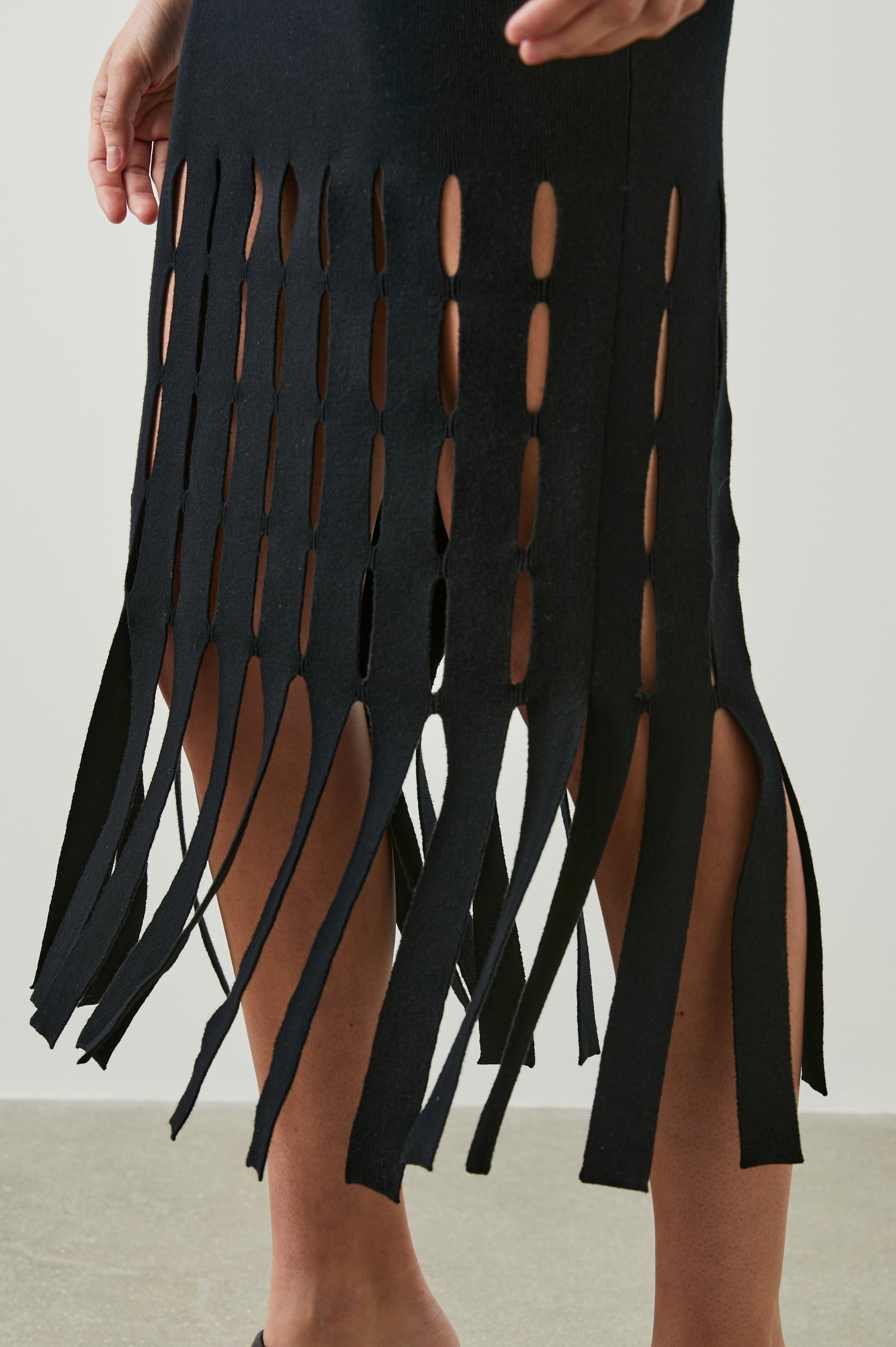 Kaia Sleeveless Midi Dress with a V Neck and Vertical Dashed Cutouts From the Thigh Downward, ending in Panels in Black Colorway - Front View Featured on Model