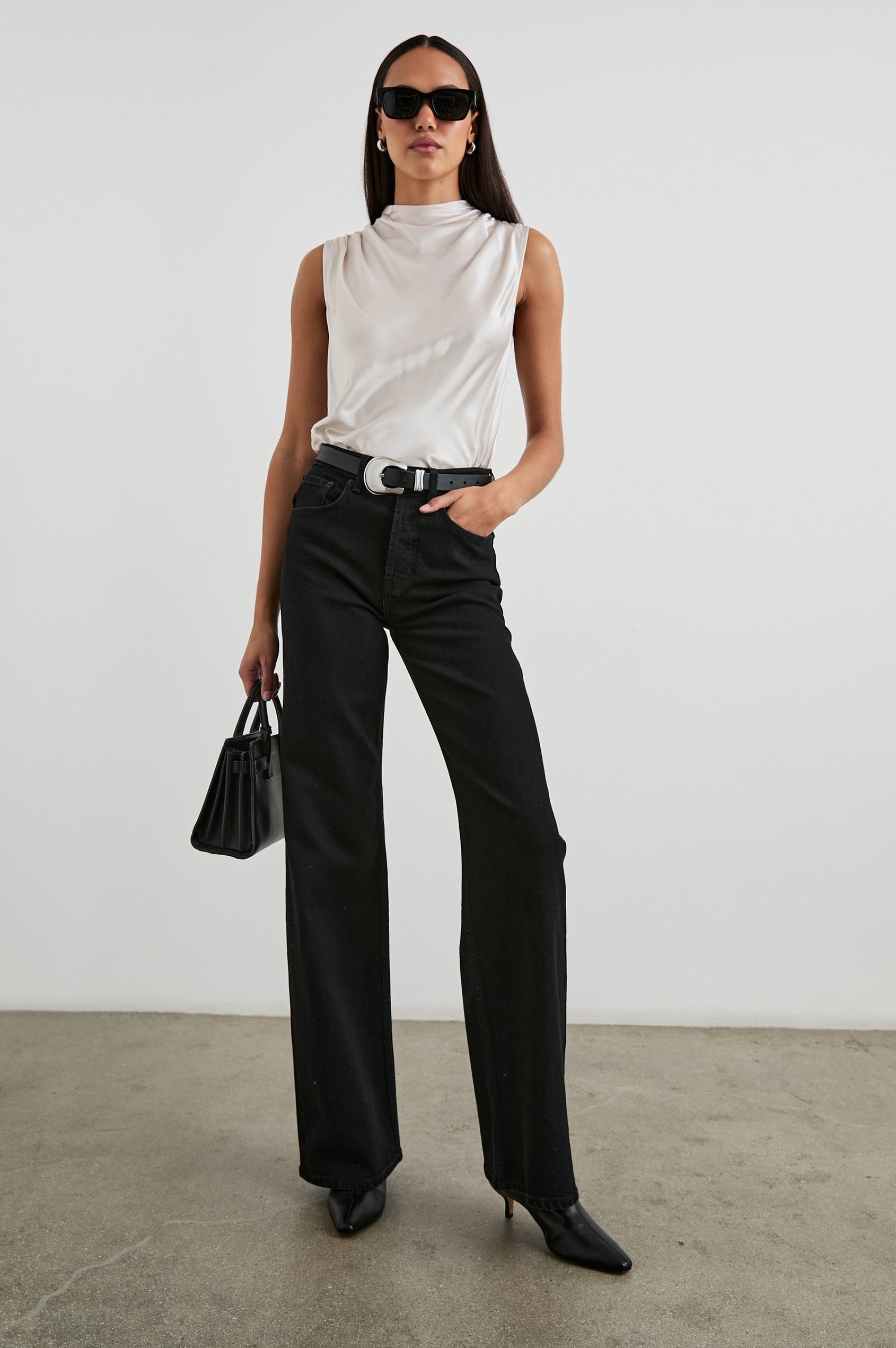 Kaleen Sleeveless Top with Mock Neck with Buttons and Keyhole on the Back and Draped Fabric on the Upper Chest in Ivory Colorway- Front Tucked Full Body View Featured on Model