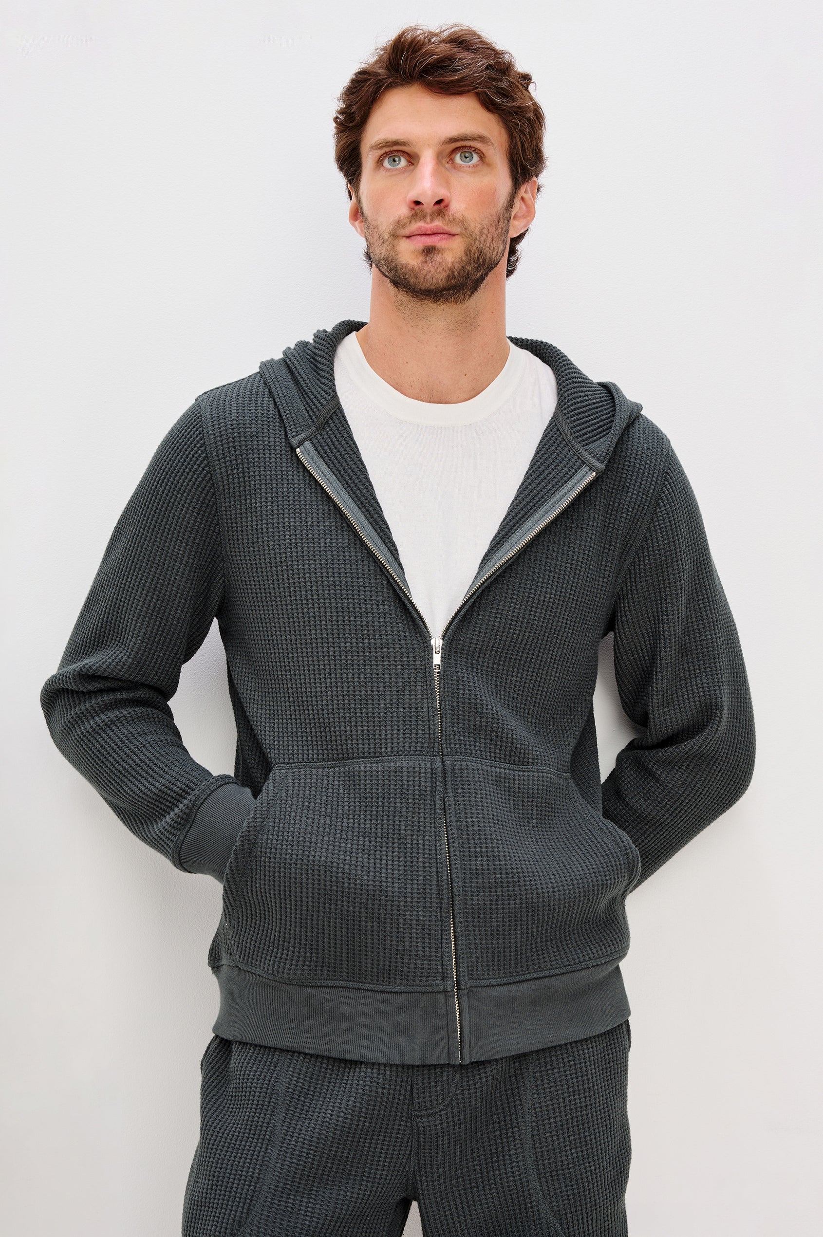 Kenton is a zip front hooded sweatshirt with front patch pockets and ribbed cuffs in Ink colorway. Front view featured on model.