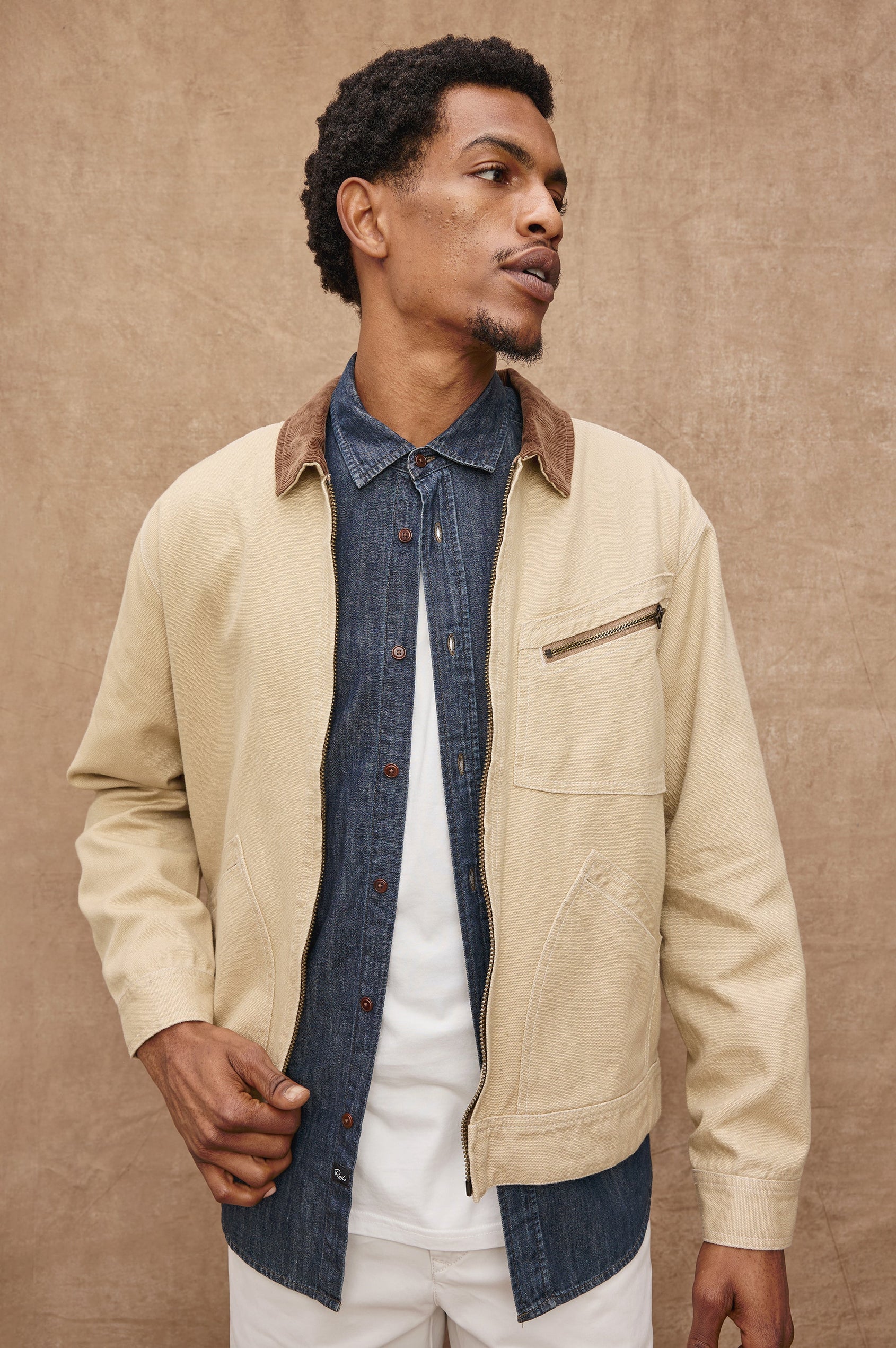 Ketter Zip Up Jacket with Two Curved Front Patch Pockets, a Diagonally Zippered Chest Patch Pocket and Adjustable Button Straps on the Hem in Duck Colorway, a Tan with a Darker Brown Collar - Front View Featured on Model