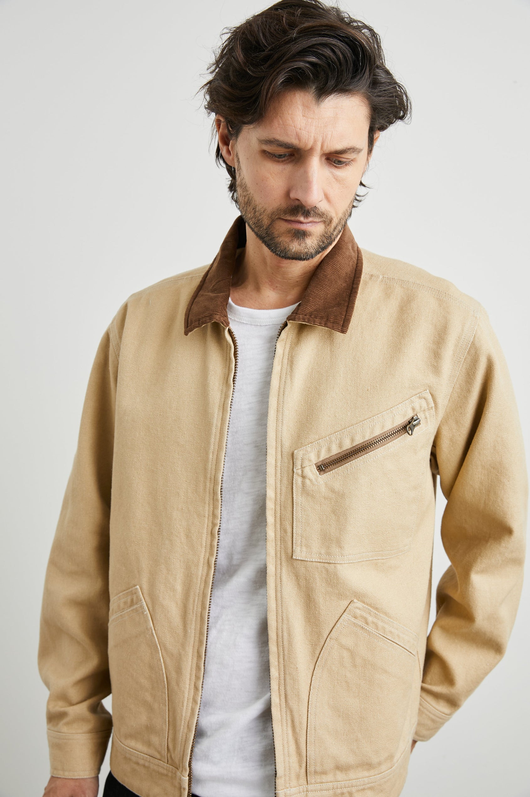 Ketter Zip Up Jacket with Two Curved Front Patch Pockets, a Diagonally Zippered Chest Patch Pocket and Adjustable Button Straps on the Hem in Duck Colorway, a Tan with a Darker Brown Collar - Front View Featured on Model