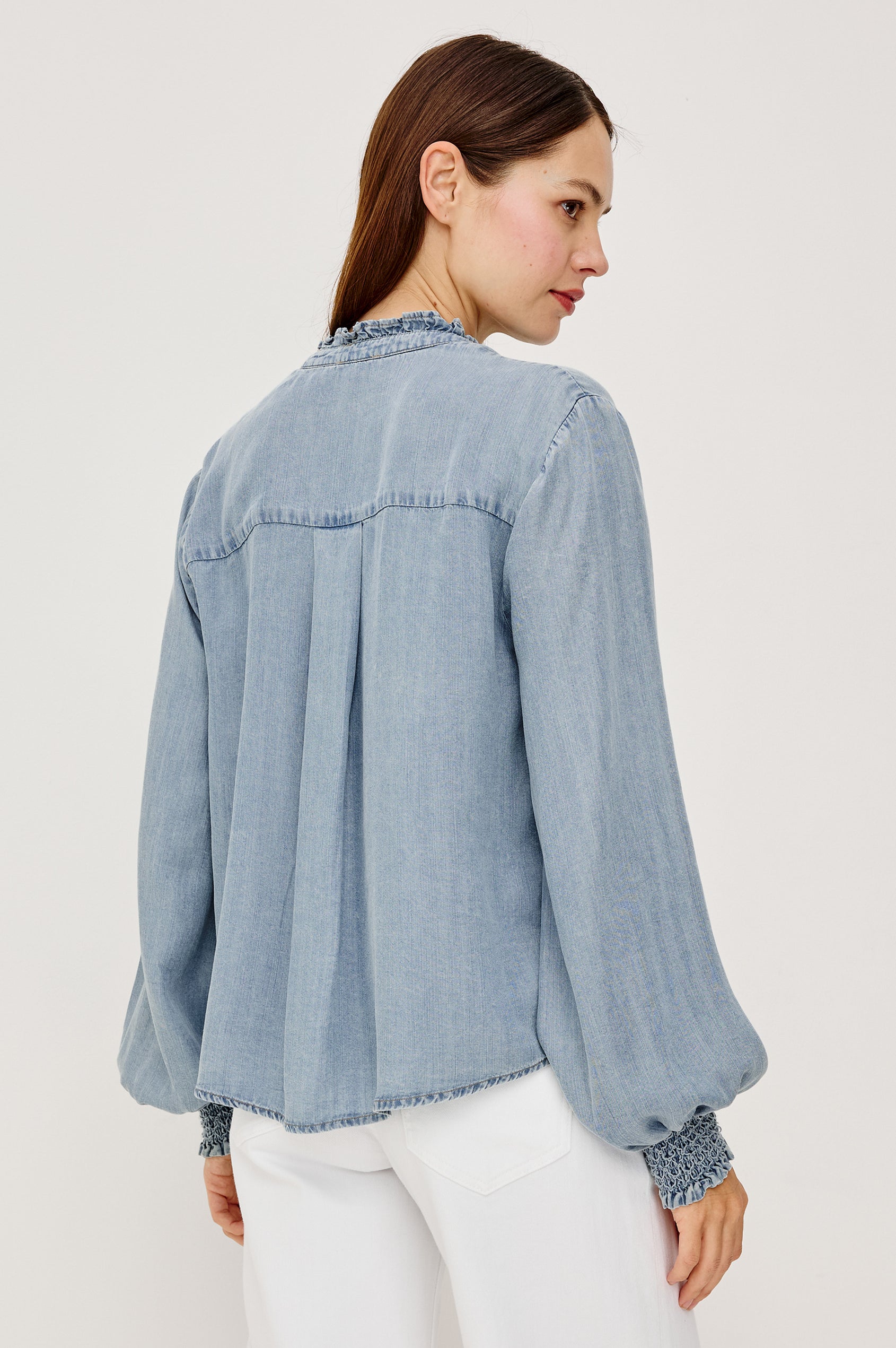 Kimmy TENCELâ„¢ Denim Top With Band Collar Half-Button Placket Long Gathered Sleeves With Smocked Cuffs and Loose Relaxed Fit in Washed Blue Colorway - Upper Body Back View Featured on Model