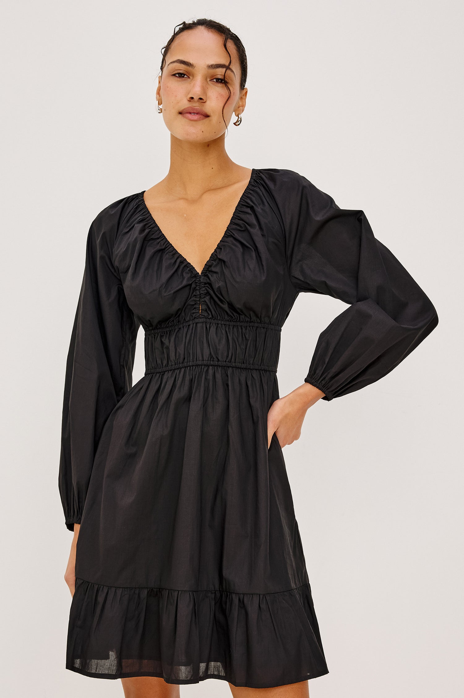 Krina Mini Dress in Cotton Poplin With Deep V-Neckline, Center Front Ties, Long Billowing Sleeves, and Tiered Hem in Black Colorway - Upper Body Front View Featured on Model