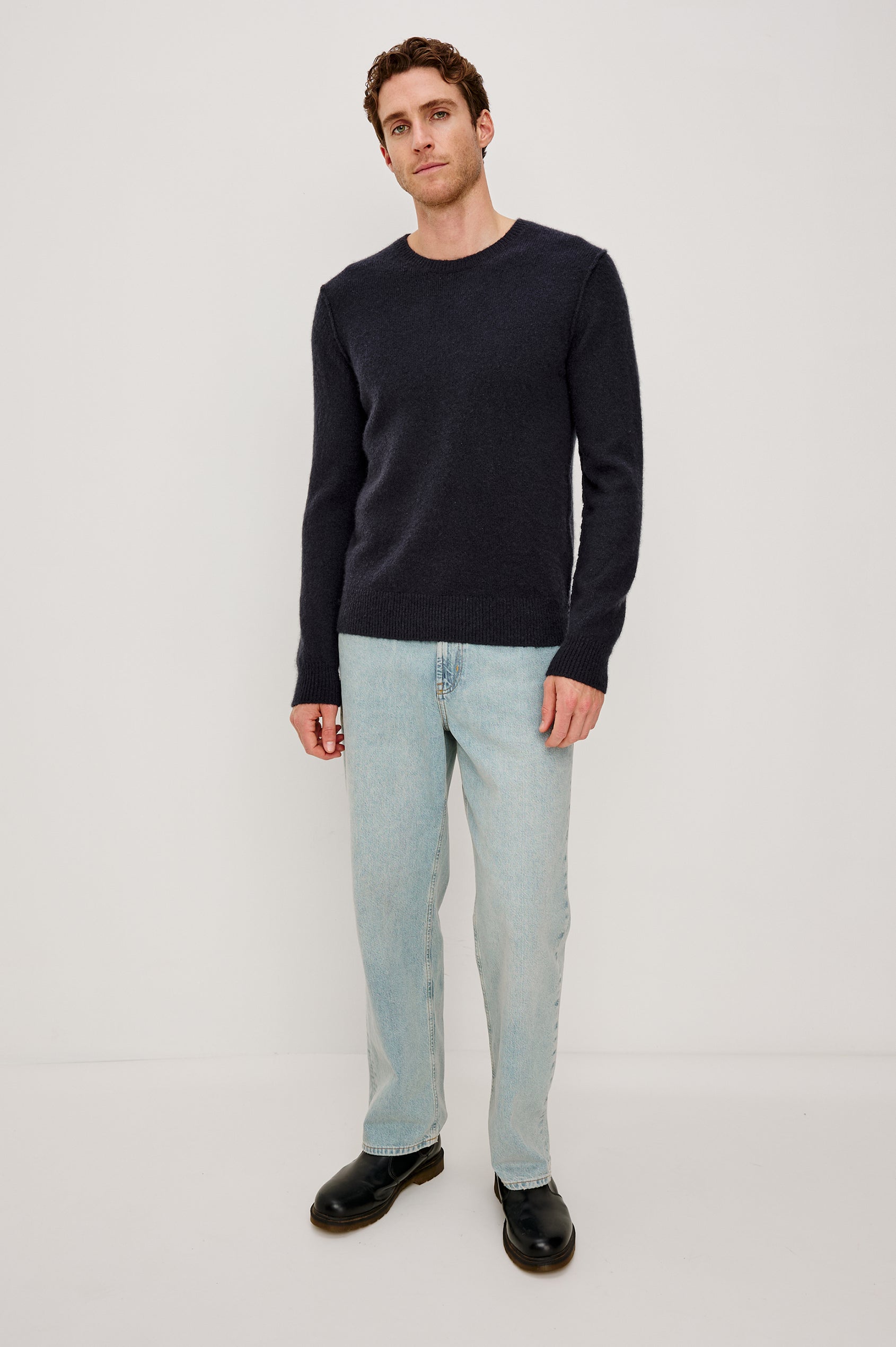 The Laurent is a relaxed-fit sweater with dropped shoulders, long sleeves, and linking-stitch detailing at the shoulders in Midnight colorway. Front full body view featured on model.