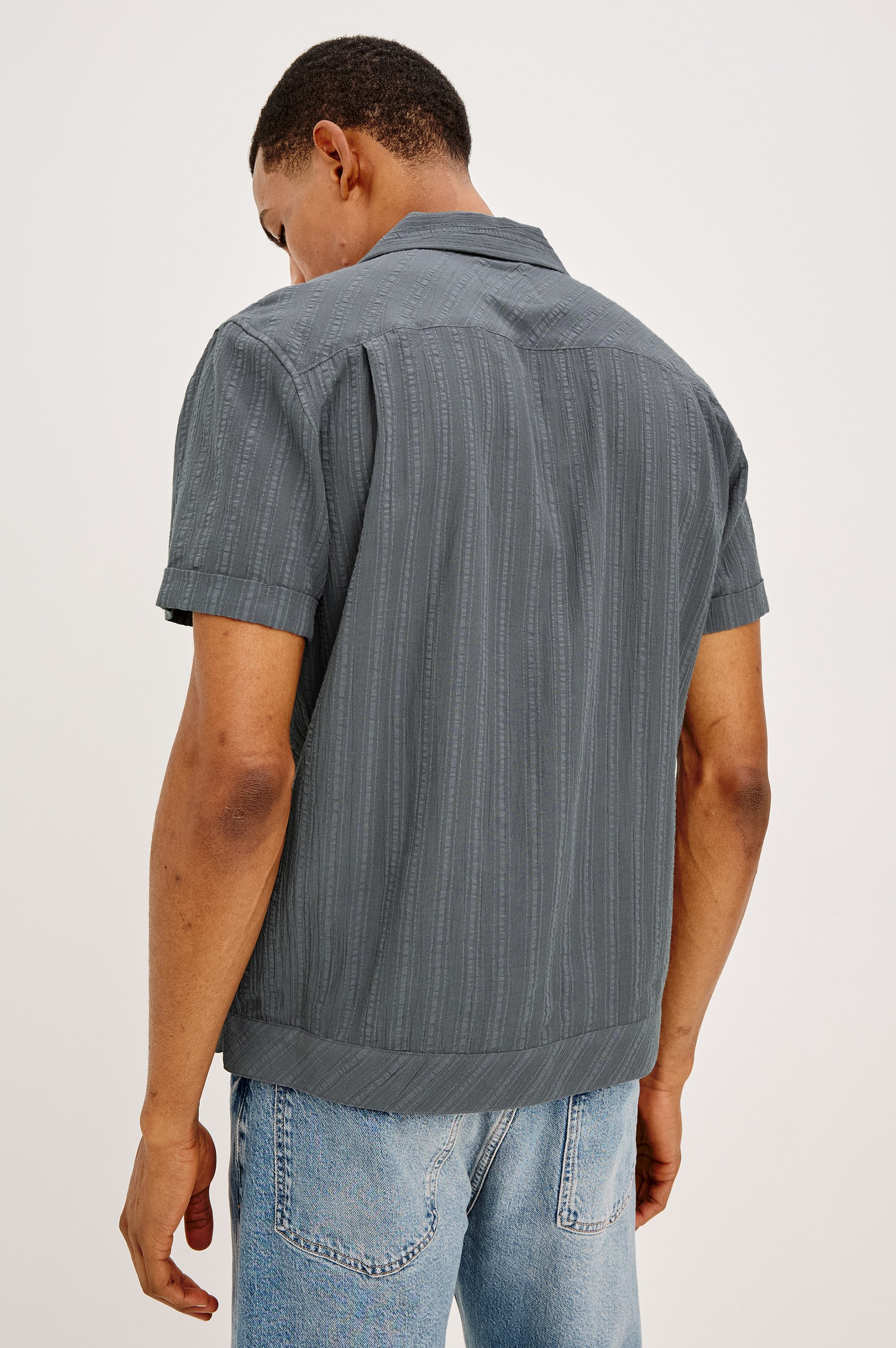 Lemmy Camp Shirt in Textured Dobby Cotton With Notched Collar, Classic Fit, Short Sleeves, and Front Buttons in Cement Blue Colorway - Upper Body Back View Featured on Model
