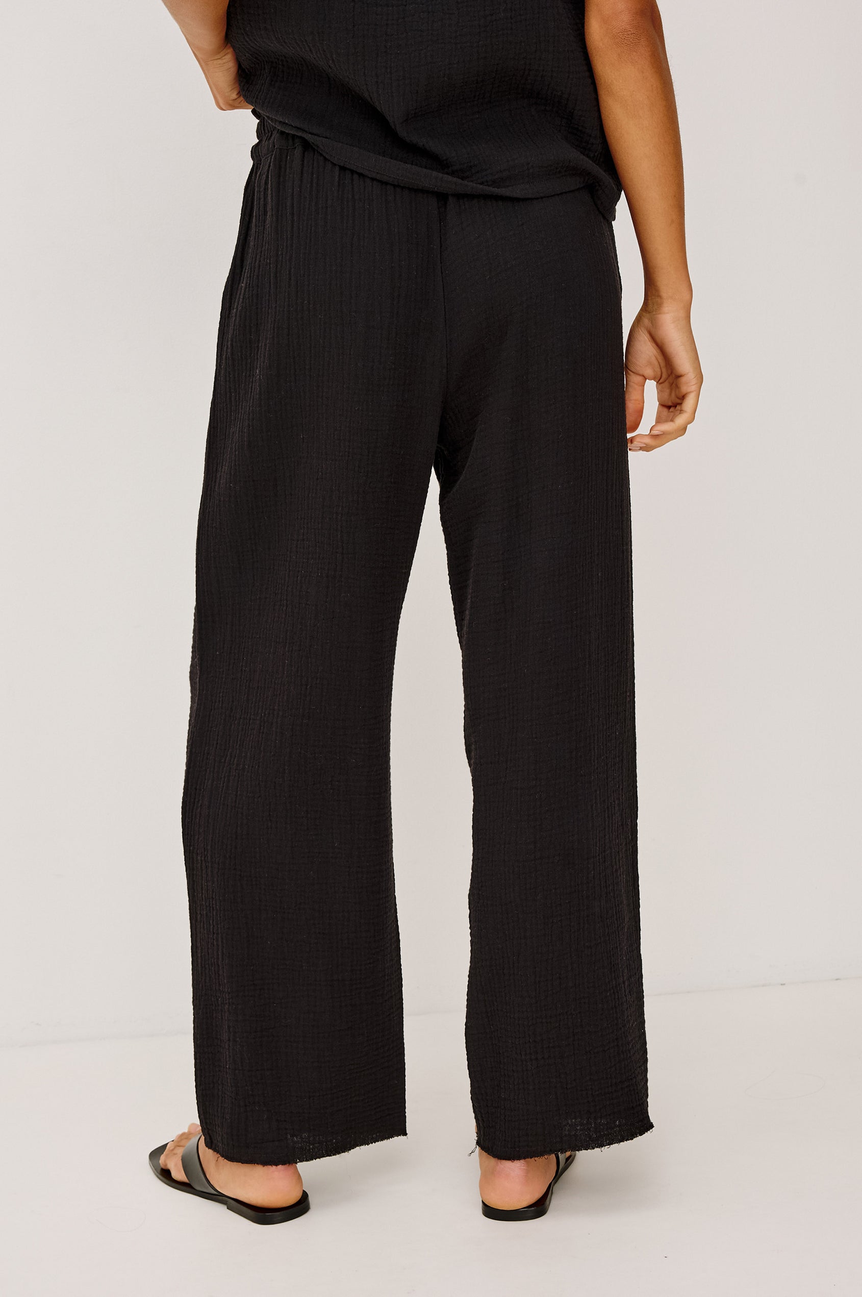Leon Crop Cotton Gauze Pant With Hemline Slit And Elastic Waist In Colorway Black - Back View Featured On Model