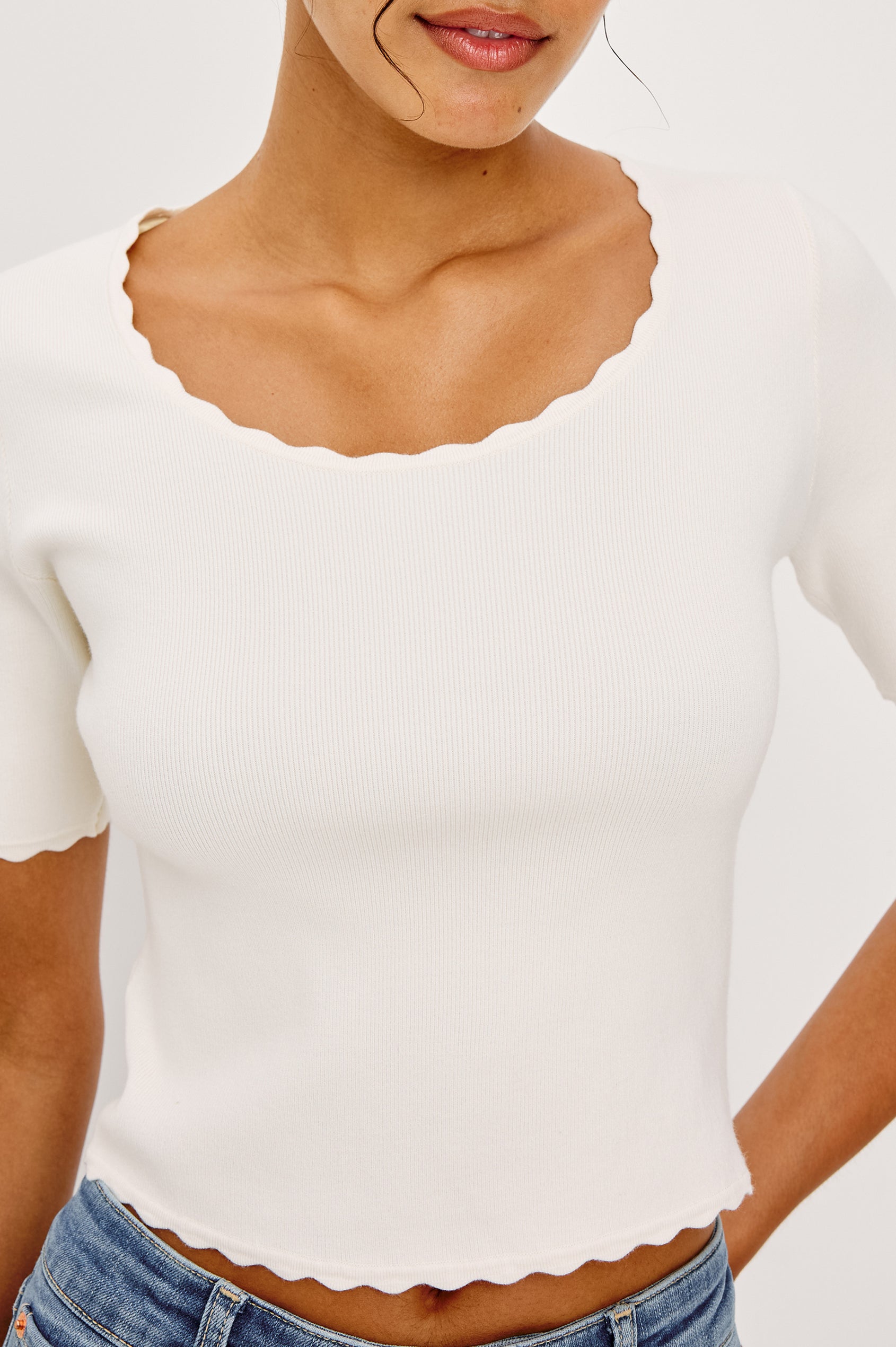 Louanna Fitted Cropped Top in Compact Knit With Scallop-Trimmed Scoop Neckline Short Sleeves and Hem in Ivory Colorway - Upper Body Close Up Front View Featured on Model
