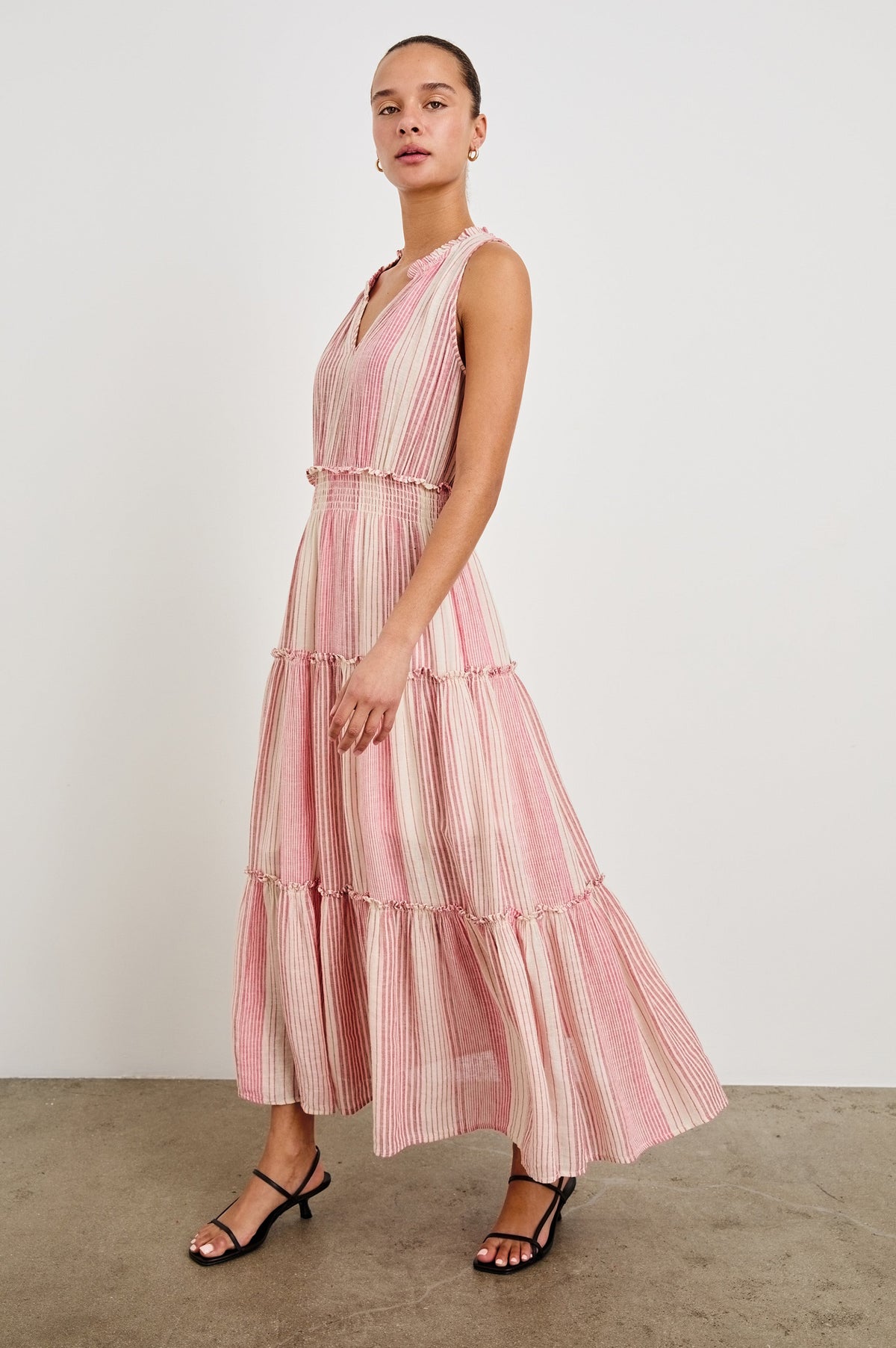 Front view of female model wearing our sleeveless, Loulou Maxi Dress in color Salerno Stripe, a pink and white boho stripe. Dress features smocked waist, v-neck, and tiered maxi skirt. 