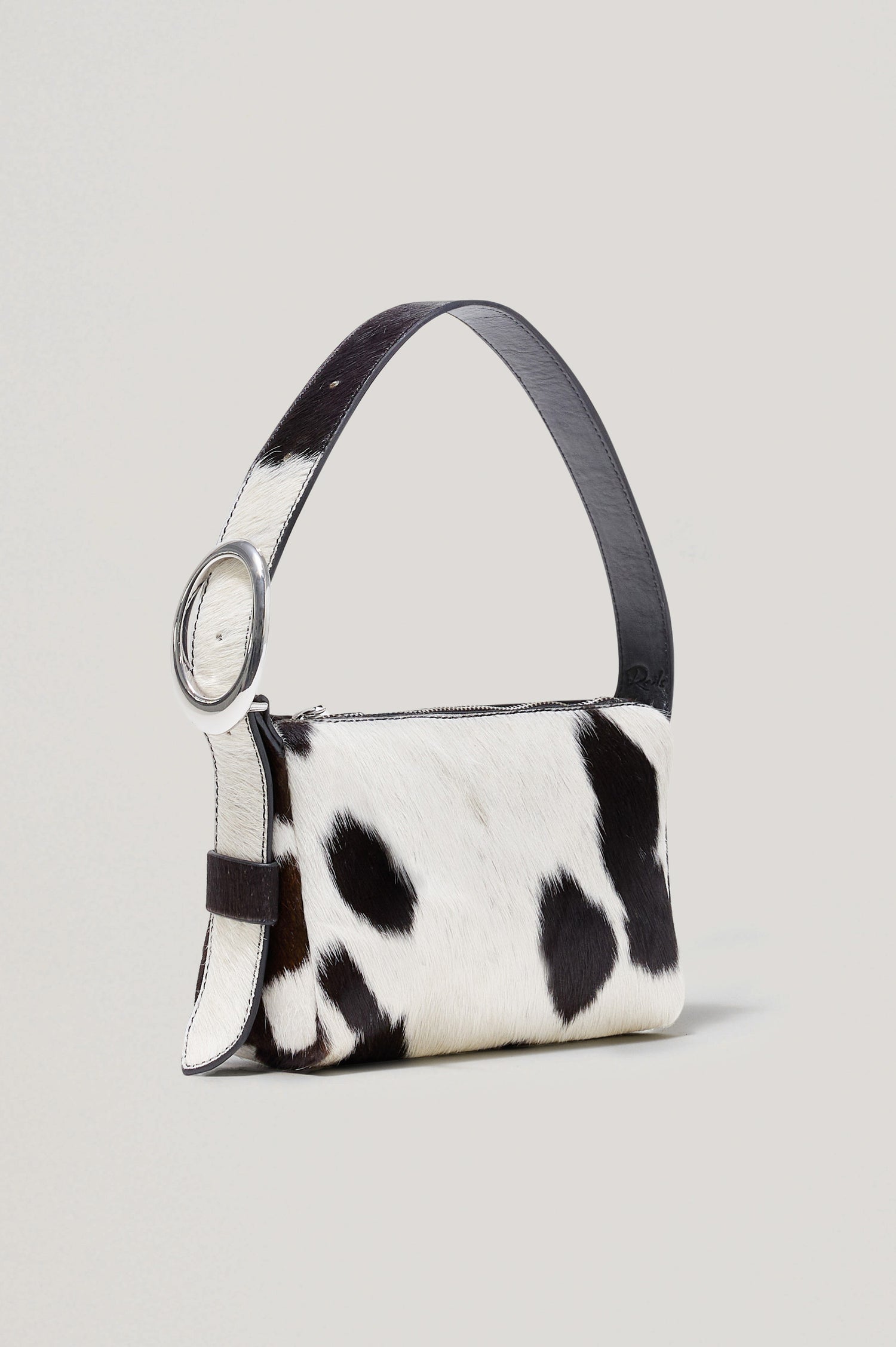 The Lucca is a long-hair cowhide shoulder bag with an adjustable strap and polished silver oval buckle. In Cowgirl Haircalf colorway. Front view featured.