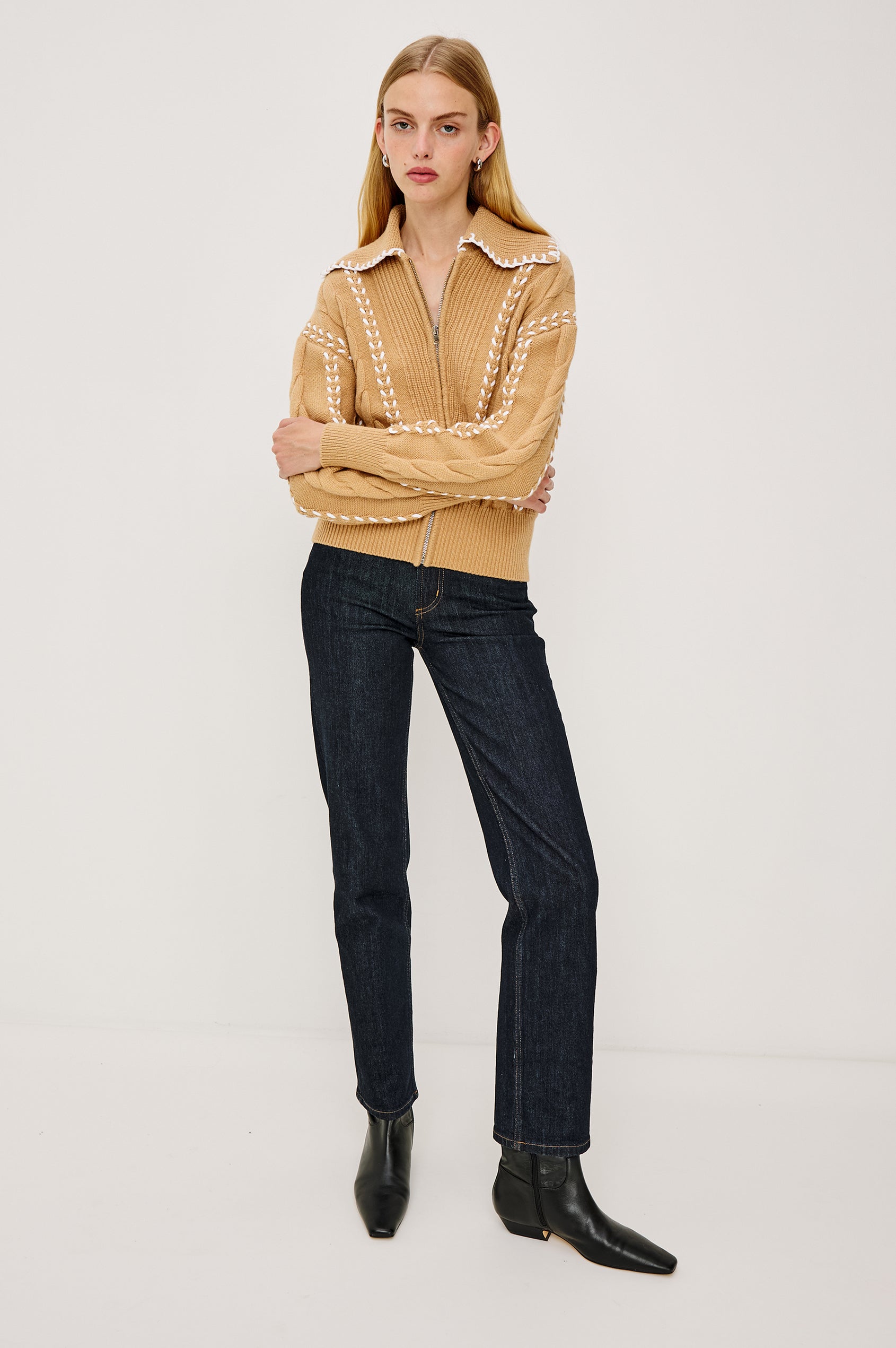 Lune Sweater in Cable Knit With Contrast Blanket Stitch Detailing, Stand Collar, Front Zipper, and Long Sleeves in Camel Ivory Blanket Stitch Colorway - Full Body Front View Featured on Model