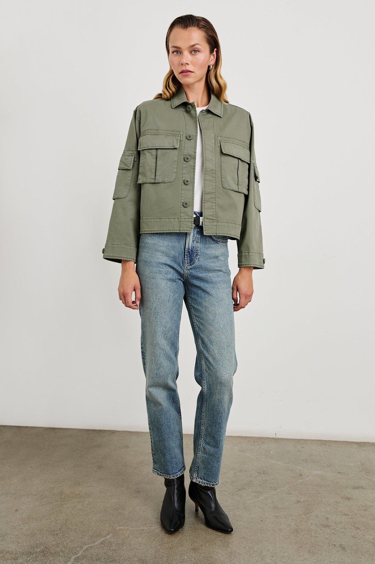 Madison Jacket with Button Closure, Two Chest Flap Pockets, Two Sleeve Flap Pockets, Adjustable Button Tab at Cuffs, and a Button Tab at Hem in Dark Olive Colorway - Front Full Body View Featured on Model  