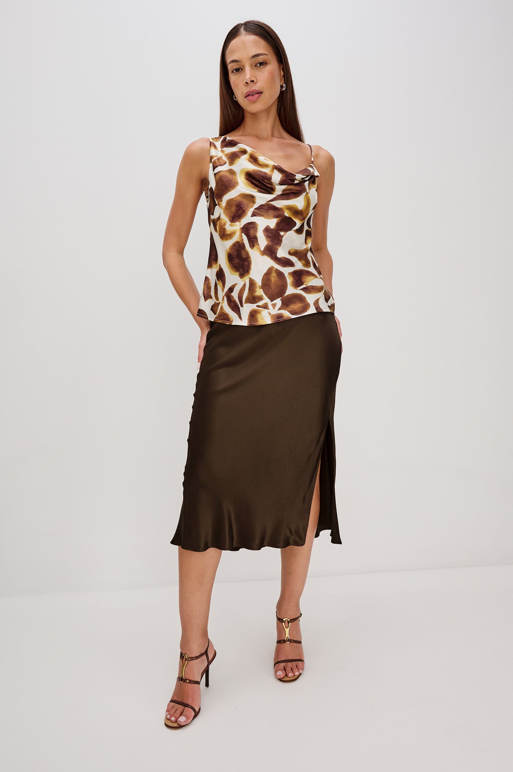 Mae is a satin-back crepe cami top with a cowl neckline and asymmetrical design. The top features one adjustable strap, creating a sleek and modern silhouette with a subtle sheen in Espresso Lily Colorway - Full Body front view featured on model