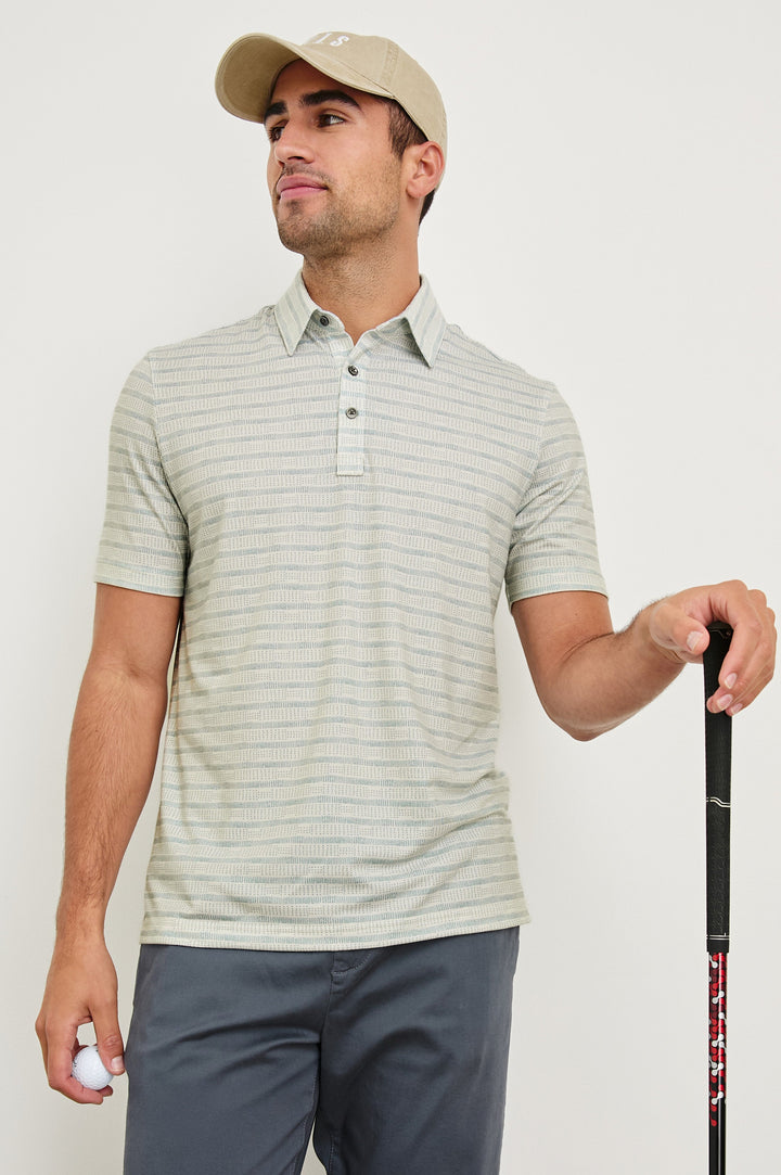 Merced short sleeve athletic Golf Polo with two button placket and collar in Sashiko Border White - front view on model wearing hat, holding golf club and ball 