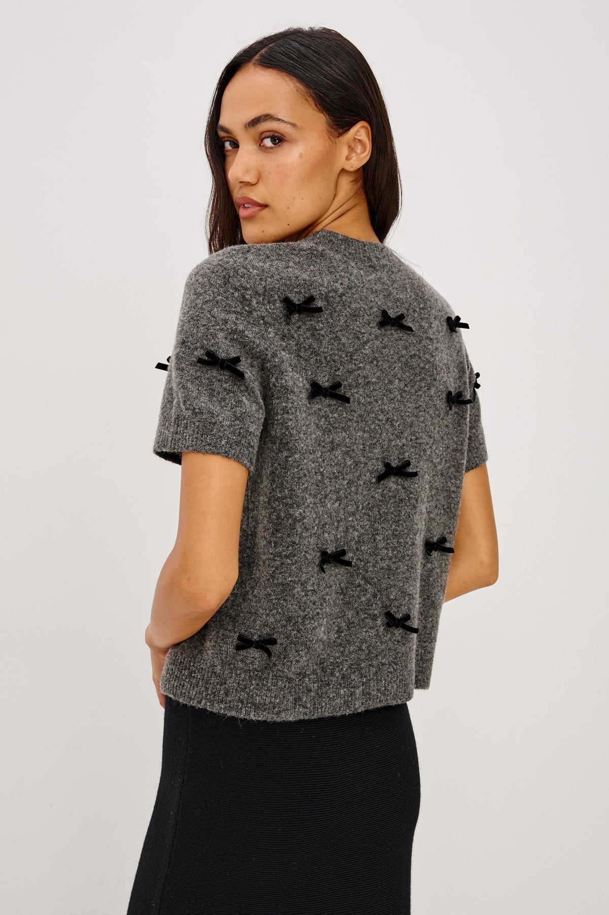 Michele Sweater in Wool Blend With an Off-The-Shoulder Neckline and Bow Applique in Charcoal Colorway - Back Crop View Featured on Model.