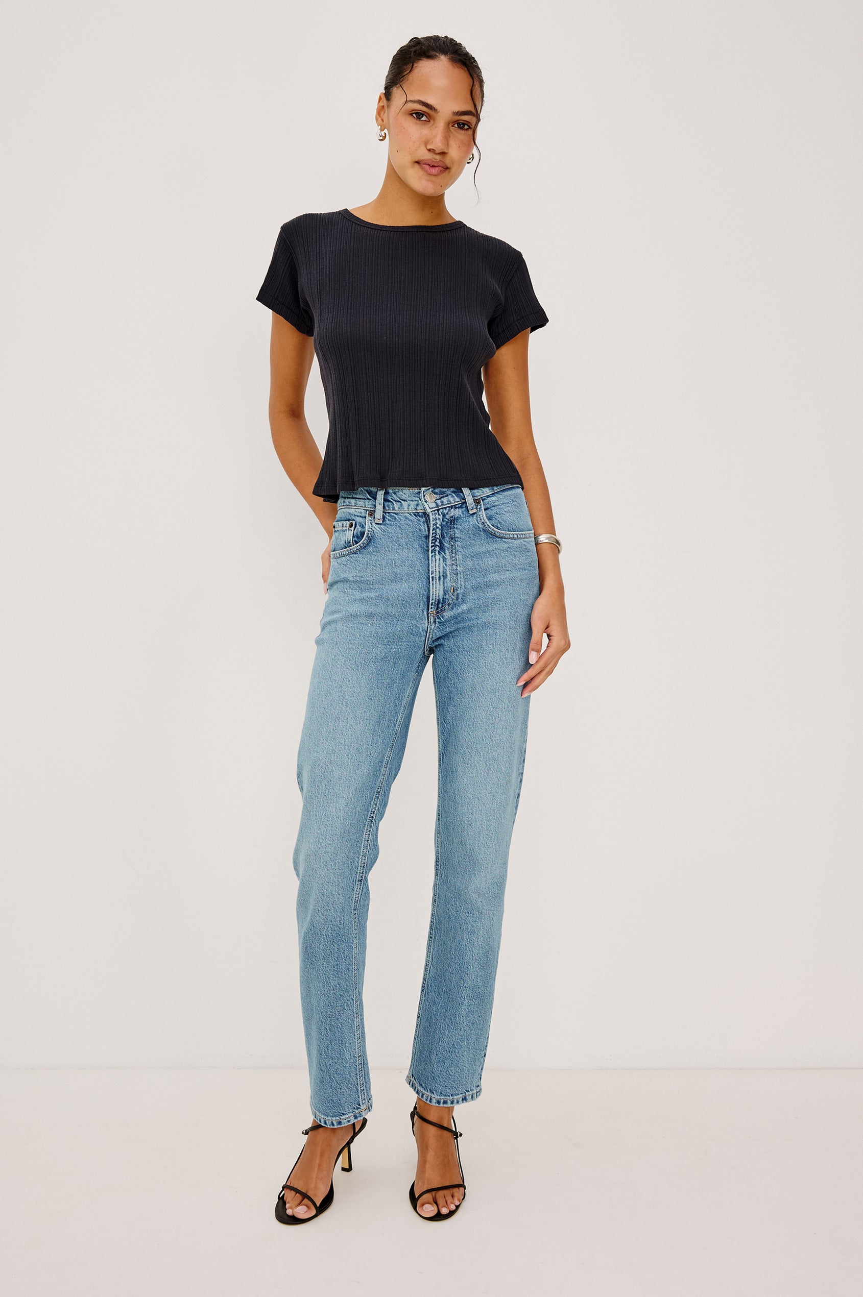 Mickey Fitted Crewneck Short Sleeve Baby Tee With Pleated Rib Pointelle Detailing in Black Colorway - Full Body Front View Stylized Featuerd on Model