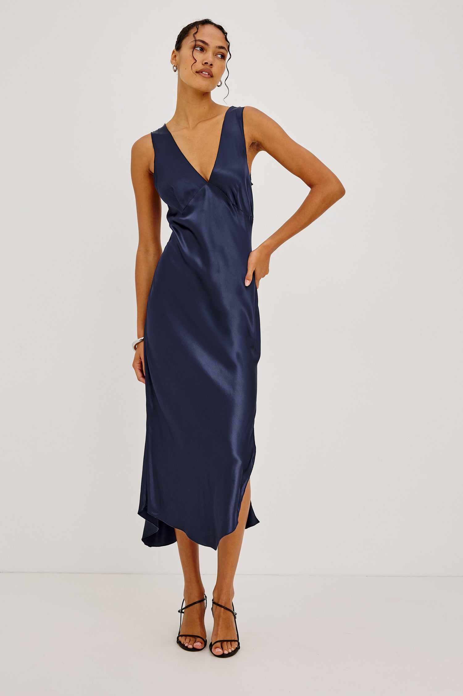 Monique Midi Bias Cut Slip Dress in Satin-Back Crepe With V-Neckline, Asymmetric Hem, and Side Slit in Navy Colorway - Full Body Front View Featured on Model