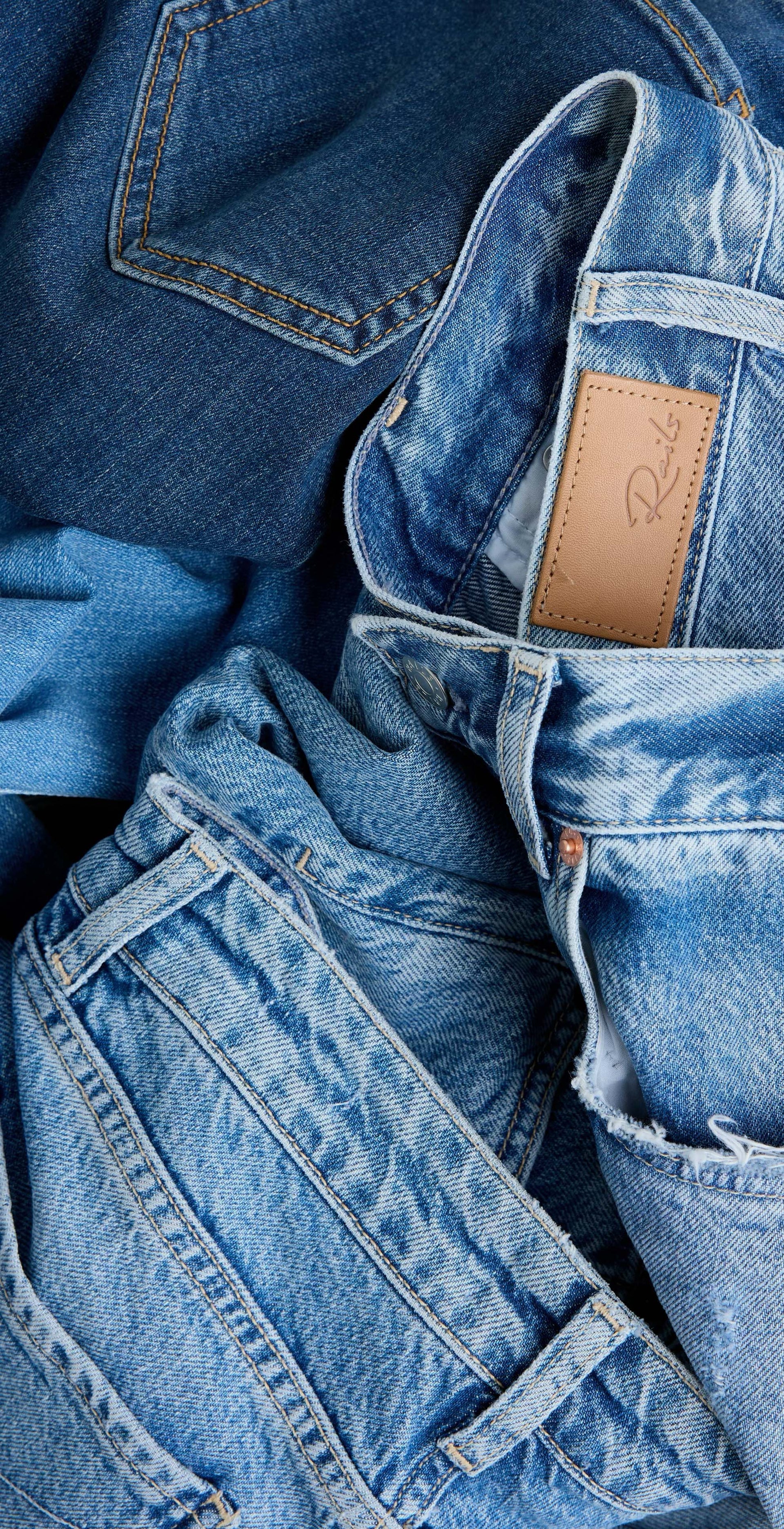 Stack of blue jeans with a brand label on a blue background